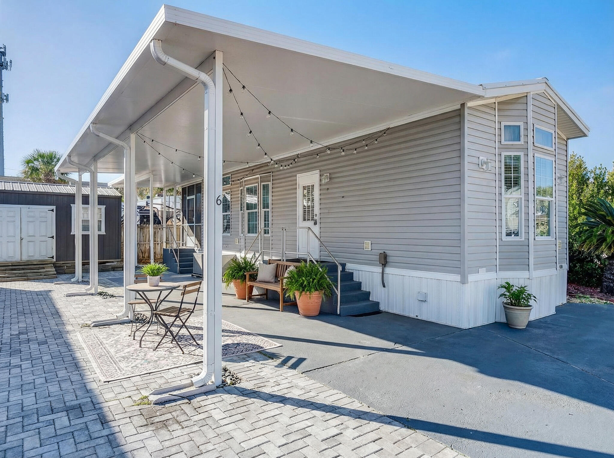 PRICED REDUCED 24K!!!! BEACHSIDE LIVING! Just a Short Stroll to the Shore of the sugar-white sandy beach. This custom ''RV Park Model'' built in 2020, features a bright, coastal-inspired design with bay and transom windows that fill the interior with natural light. A metal roof, expansive covered carport, pavers, composite deck NEWLY screened-in deck, all provide wonderful spaces to relax and entertain outdoors. Inside, you'll find beautiful LVP flooring paired with a crisp white/grey palette, coffered and 9-foot ceilings, with smart creative storage throughout. The floor plan is open to the kitchen, breakfast, and living area which flows onto the added 104 SqFt covered screened in deck. The bathroom has been thoughtfully updated with a tub-to-shower remodel, offering a sleek, modern feel and added convenience. The bright, airy bedroom includes built-in closets and dresser for added storage. An EXTRA 112 SQ FT of heated, cooled and insulated multi-purpose outbuilding creates the perfect bonus space, ideal for extra storage, hobby room or peaceful hideaway just steps from the main home. Perfectly sized paved patio includes a hot and cold outdoor shower to rinse off after beach days with an added  extra storage unit included. Situated in a strictly non-rental community for enhanced privacy, and conveniently close to shopping and locals favorite dining. Walk just a couple blocks or take your golf cart to the beach or Pompano Joe's in five minutes or less! Come see this hideaway retreat!