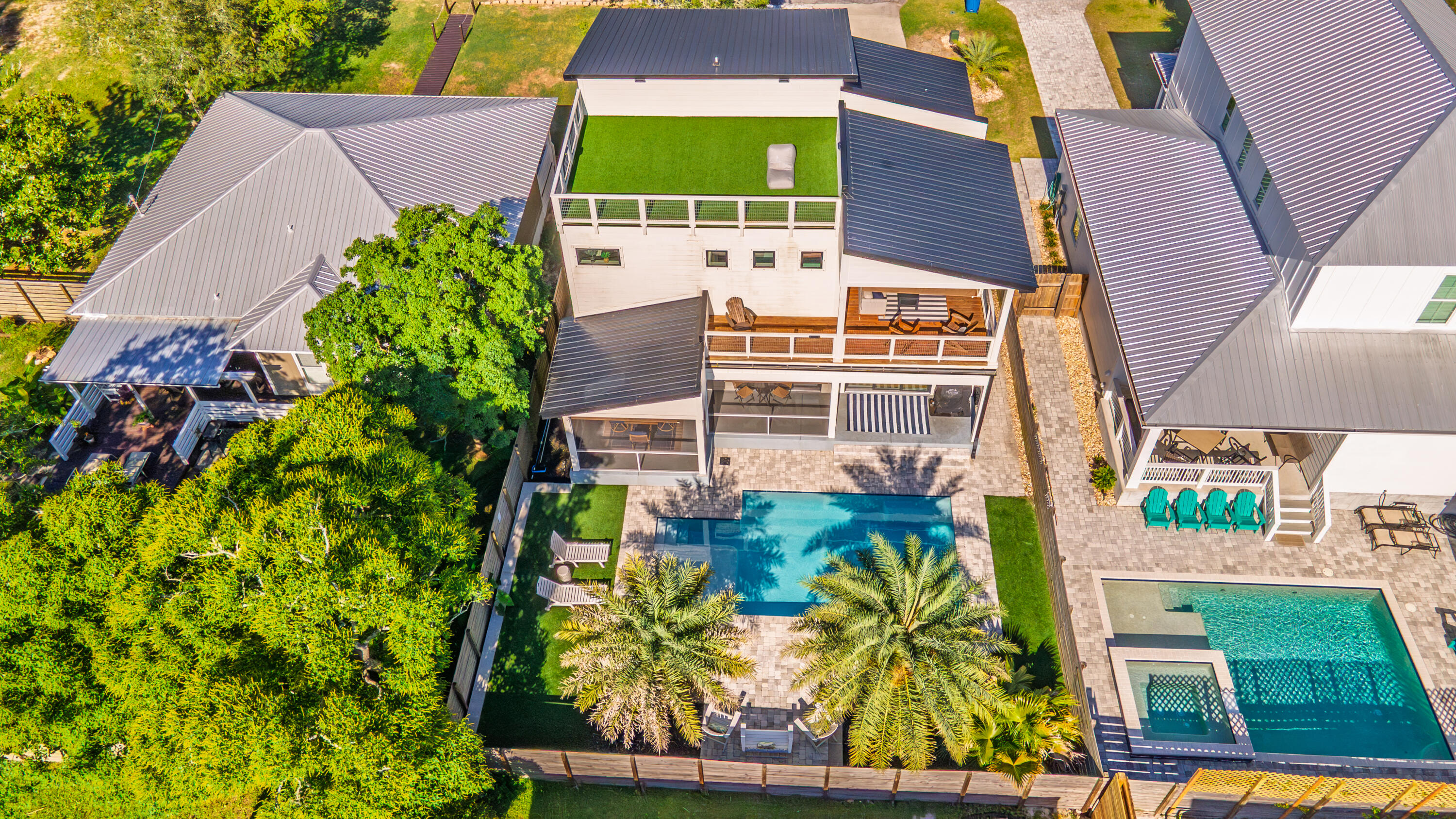 Welcome to 213 Pinetree Drive, a fully furnished contemporary beach retreat completed in 2021 and thoughtfully designed for coastal living. Located just a short walk from the sugar-white sands of Panama City Beach, this exceptional home offers the perfect blend of modern comfort, outdoor entertaining, and investment potential.

Designed to embrace the Florida lifestyle, the property features multiple outdoor living spaces, including covered porches, spacious decks, a screened lanai, and a private pool surrounded by a stone-paver terrace and sun deck. A rooftop observation deck provides the perfect place to relax, enjoy Gulf breezes, and take in glimpses of the water.

Inside, light-filled living spaces create a welcoming atmosphere throughout. The main living area features hardwood flooring, comfortable seating, a striking media wall, built-in bookshelves, and a cozy fireplace framed by clerestory windows. The open-concept layout flows seamlessly into the dining area and beautifully appointed kitchen, where quartz countertops, a large center island, stainless steel appliances, abundant cabinetry, and a pantry offer both style and functionality.

The thoughtfully designed floor plan includes a spacious guest bedroom and full bath on the first floor, providing convenience and privacy for guests or multigenerational living. Upstairs, you'll find two additional bedrooms, including the luxurious primary suite, which features private balcony access and a beautifully appointed ensuite bath complete with sleek finishes, shower, dual vanities, a freestanding soaking tub and a large walk-in closet. The additional upstairs bedroom offers comfortable accommodations for family and guests, while the home's well-designed bathrooms blend modern elegance with everyday functionality.

Additional outdoor living space on the second-floor deck connects to the rooftop observation deck, creating multiple areas to gather, entertain, or unwind while enjoying the coastal breeze.

Every inch of the home has been carefully utilized, including a dedicated laundry room and a convenient office nook tucked beneath the staircase. The attached garage offers ample storage for beach gear, bicycles, and pool accessories, while the driveway provides additional parking. Modern conveniences include LED lighting throughout and a Tesla fast charger.

Whether you're searching for a primary residence, second home, or income-producing vacation rental, this turnkey property offers an outstanding opportunity to enjoy the best of Panama City Beach living just moments from the Gulf.