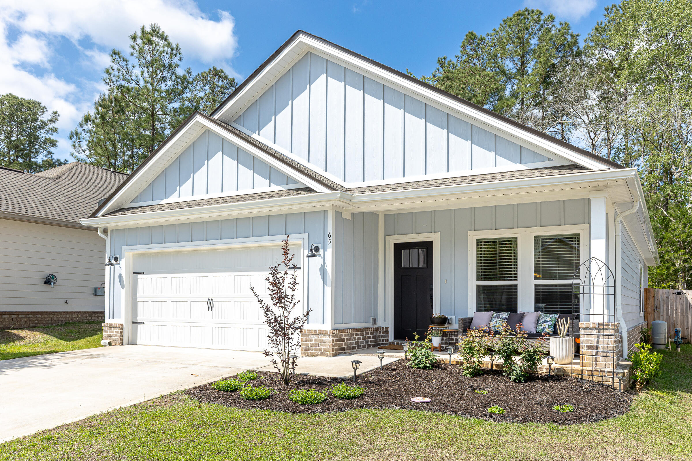 Built in 2024, this like-new home offers modern construction with thoughtful upgrades already in place. Cozy front and rear porches create the perfect setting for relaxing or entertaining, complemented by a privacy-fenced backyard, sprinkler system, and beautifully enhanced landscaping. Inside, the open-concept floor plan is highlighted by raised ceilings, recessed lighting, and LVP flooring throughout. The kitchen features a spacious work island with dining space, granite countertops, contrasting white and black shaker cabinetry, stainless steel appliances, pantry, and a luxurious Bespoke Samsung refrigerator. The split-bedroom layout provides added privacy, with a well-appointed primary suite offering double vanities, a tiled walk-in shower with upgraded glass enclosure, a walk-in closet with custom buildouts, and a linen closet. Additional upgrades include custom closet systems in every bedroom, added kitchen shelving, new door hardware, gutters with French drains, enhanced garden beds, and a digital front door lock--making this home truly move-in ready. The neighborhood features sidewalks, a community pool, park area and a prime location with convenient access to Hwy 20 and Hwy 331, as well as the nearby Publix shopping center. Just a 20 minute drive to the beaches of 30A!