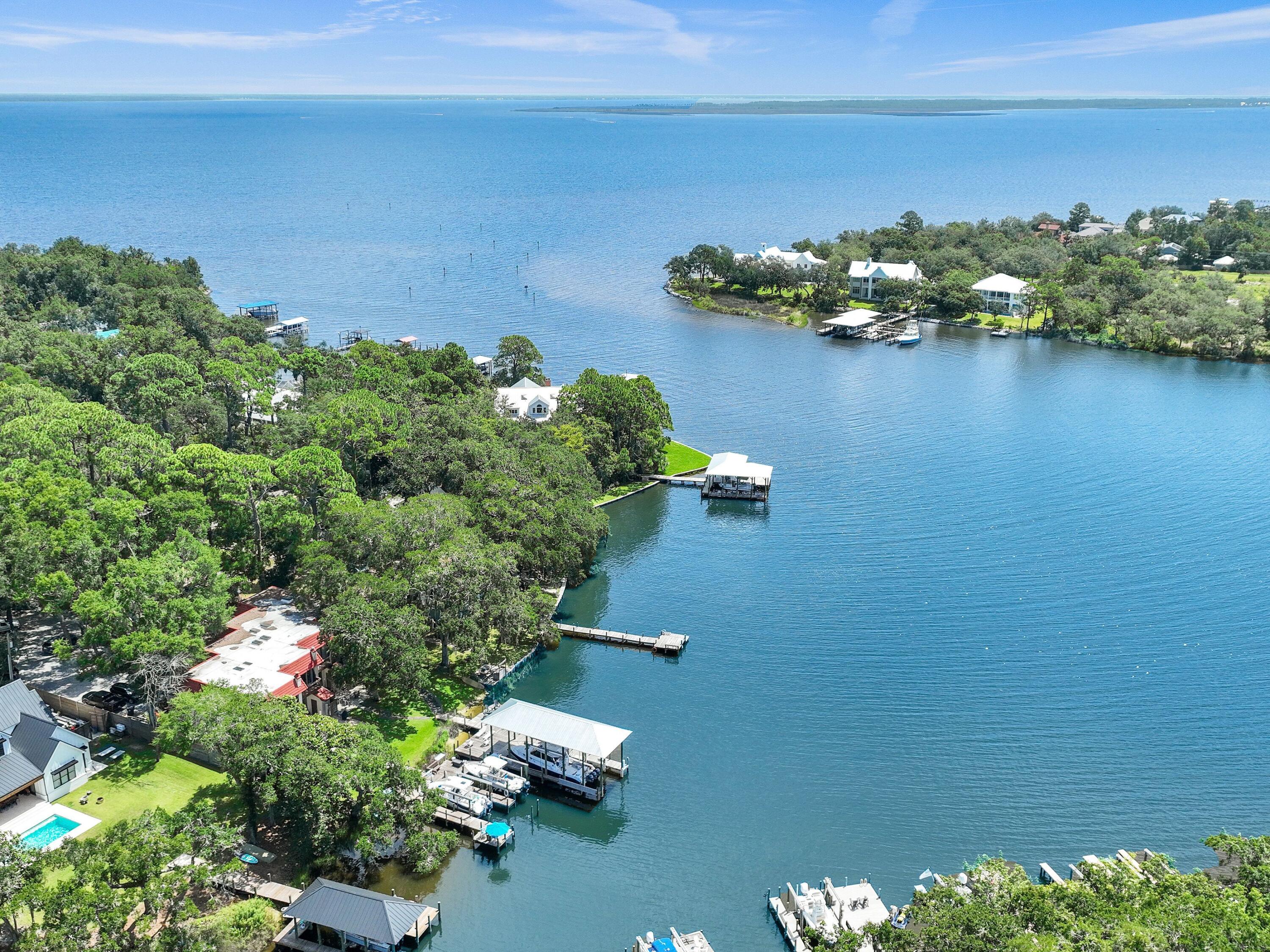 Wake up each morning to peaceful waterfront views and end every evening with breathtaking sunsets that paint the sky in brilliant shades of orange, pink, and blue. From your private dock, you'll enjoy a front-row seat to one of nature's most spectacular shows as dolphins regularly swim through Mack Bayou, playing and feeding just offshore, while a majestic blue heron makes daily visits to fish from the dock. Whether you're sipping your morning coffee, unwinding with a glass of wine at sunset, or simply enjoying the sights and sounds of the water, this home offers an ever-changing display of coastal wildlife and the relaxed waterfront lifestyle you've been dreaming of. Deep-water dockage, open bay views, and exceptional coastal living await at this beautifully maintained waterfront townhome on Mack Bayou in Santa Rosa Beach. Nestled within an exclusive enclave of only four residences, this exceptional 2-bedroom, 2.5-bath home offers approximately 1,600 square feet of thoughtfully designed living space along with the rare opportunity for both personal enjoyment and investment, as short-term rentals are permitted. Situated on 100 feet of shared bayou frontage with expansive open bay views, each residence enjoys a shared 40-foot dock, dedicated boat slip, and boat lift. With approximately four feet of water depth year-round, the slip easily accommodates larger boats, allowing you to spend more time on the water and less time worrying about the tides. A convenient fish-cleaning station makes returning from a successful day on the water effortless, and the seller's 26-foot boat, currently housed in the slip, is available for purchase separately. Inside, natural light pours through an impressive, oversized skylight, illuminating the open-concept living and dining areas. The custom kitchen was designed with entertaining in mind and features solid wood shaker cabinetry with soft-close doors and drawers, a wet bar, beverage refrigerator, and refrigerator with in-door water and ice dispenser. The spacious waterfront primary suite offers a peaceful retreat with sliding glass doors leading to a private balcony overlooking the bayou. Even the primary bathroom embraces the waterfront setting, featuring dual vanities and tranquil water views that make every day feel like a vacation. Outdoor living is equally impressive with expansive brick-pavered front and rear porches, an outdoor shower for rinsing off after a day on the boat or at the beach, and both front and rear storage rooms perfect for fishing gear, paddleboards, beach equipment, and more. The front porch even includes a dedicated water supply for potted plants and seasonal flowers. Quality craftsmanship is evident throughout with hardwood flooring on the main level and staircase, new luxury vinyl plank flooring upstairs, solid-core interior doors, elegant 8-inch baseboards, a Tesla electric vehicle charger, heavy-duty stair handrail, new fencing, a new electrical panel, and a recently replaced well pump. Major improvements provide added peace of mind, including a 2017 roof, 2022 18 sear Mitsubishi true variable air conditioner / heat pump, 2020 water heater, and a brand-new community septic tank and drain field installed in 2025. Owners share the cost of lawn maintenance, pest control, common area irrigation, water and electricity to the docks, and umbrella insurance for the building, allowing for a convenient, low-maintenance waterfront lifestyle. Two dedicated parking spaces are located directly in front of the residence, and the prime Santa Rosa Beach location places you just minutes from the sugar-white beaches of Scenic Highway 30A, Grand Boulevard, Sacred Heart Hospital, premier shopping, dining, golf, and entertainment. Whether you're searching for a primary residence, a second home, or an income-producing investment, this rare waterfront offering combines deep-water boating, private boat slip and lift, spectacular sunsets, abundant coastal wildlife, and an unmatched waterfront lifestyle in one truly remarkable property.