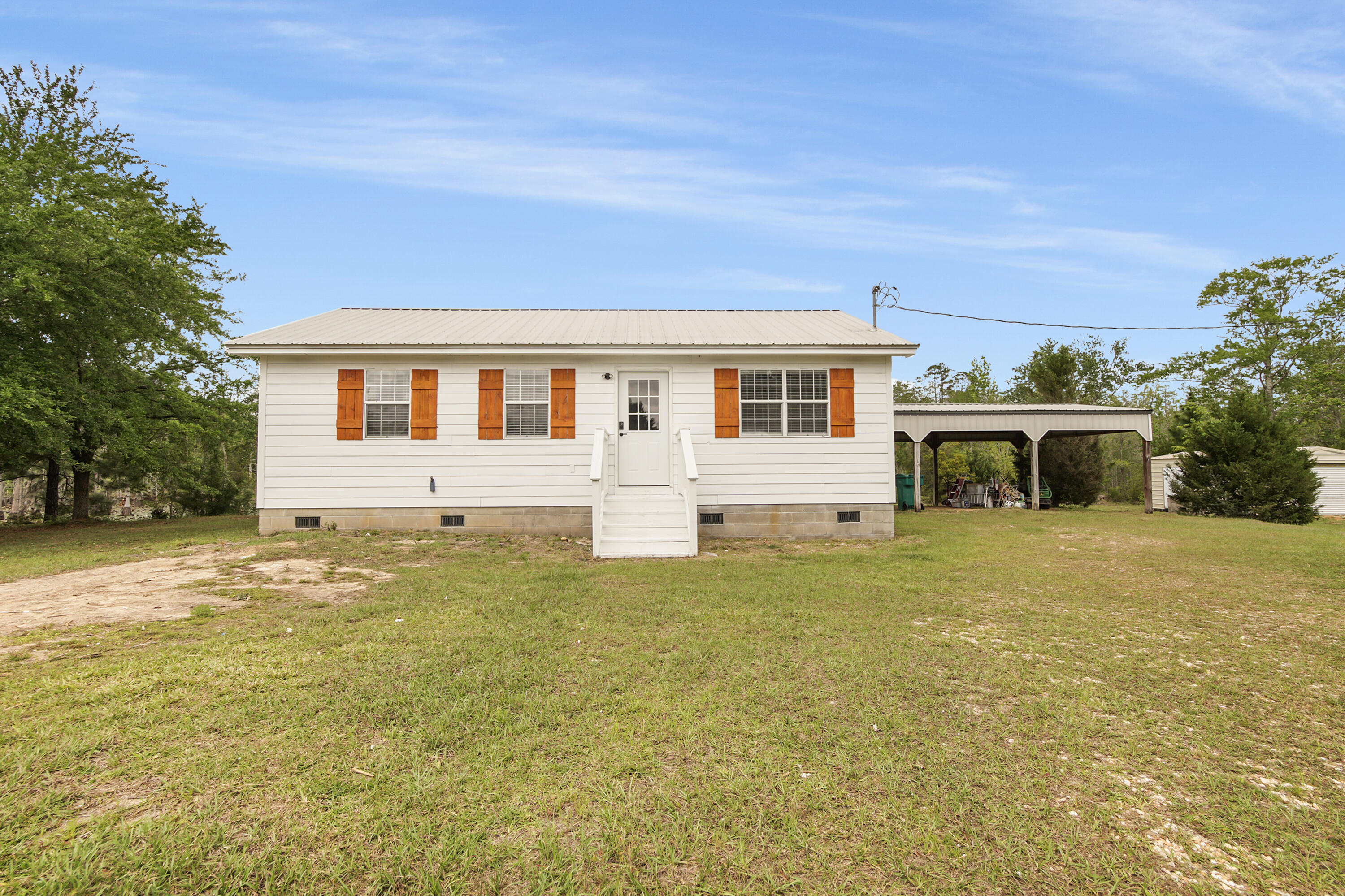 Nestled on a beautiful and expansive 11-acre tract, 2328 Pioneer Rd in Chipley, FL offers the perfect blend of privacy, functionality, and modern updates--creating an ideal setting for country living with convenience just minutes away. This freshly updated 3-bedroom, 1-bath home is move-in ready and perfectly suited for those seeking space, scenic views, and versatility.

As you arrive, you'll immediately appreciate the peaceful surroundings and wide-open acreage that provide endless possibilities--whether you envision a mini farm, recreational retreat, or simply room to roam and enjoy nature. The property offers a rare combination of usable land, privacy, and proximity to town, located just minutes from downtown Wausau for easy access to local shops, dining, and everyday essentials.
 Inside, the home has been thoughtfully refreshed with a series of recent upgrades that give it a clean, modern feel while maintaining its cozy charm. Fresh interior paint brightens the space, complemented by all-new flooring that flows throughout the home. Updated fixtures add a stylish touch, and a brand-new hot water heater provides peace of mind for years to come.

The layout is both functional and inviting, featuring a comfortable living area that serves as the heart of the home. The kitchen and dining spaces are conveniently arranged, making daily living and entertaining easy and efficient. Each of the three bedrooms offers flexibility for family, guests, or even a home office setup, while the full bathroom is centrally located for convenience.
Step outside and prepare to be impressed by one of the property's standout features--a massive back deck overlooking serene water views. This outdoor space is truly special, offering the perfect setting for morning coffee, evening sunsets, or hosting gatherings with friends and family. The peaceful water backdrop enhances the overall tranquility of the property, making it easy to relax and unwind right in your own backyard.

For those needing storage, workspace, or room for vehicles and equipment, this property delivers. A large 3-vehicle detached carport provides ample covered parking, while the detached garage/workshop is ideal for hobbies, projects, or additional storage. Whether you're a craftsman, outdoor enthusiast, or simply need extra space, these structures add incredible functionality and value.
The home is serviced by city water and septic, offering a practical combination of convenience and independence. With plenty of acreage to expand, garden, or explore, the property is well-suited for a variety of lifestyles--from those seeking a quiet rural escape to buyers looking for land with future potential.

If you've been searching for an updated home on acreage with water views, functional outbuildings, and a peaceful setting close to town, 2328 Pioneer Rd is a must-see. This property captures the essence of Northwest Florida living--space, simplicity, and natural beauty--all in one exceptional package.