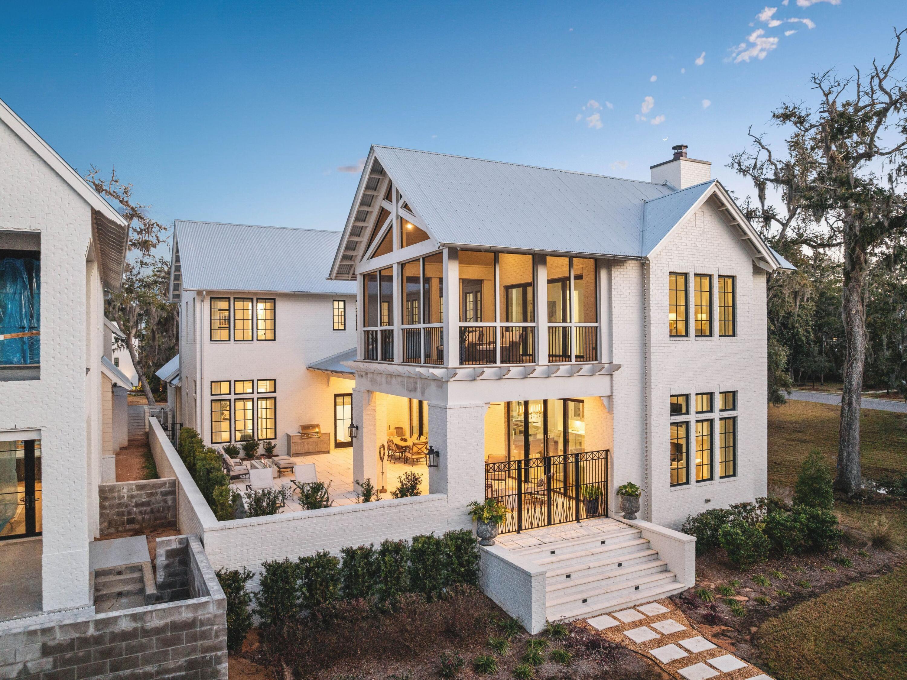 Set within the gates of Churchill Oaks, this thoughtfully designed residence captures peaceful bayou views and a level of craftsmanship rarely found. Architectural details such as arched doorways, a vaulted two-car garage, and decorative rain-chain downspouts establish the home's distinctive character, while light oak flooring, Restoration Hardware lighting, and a grand motorized foyer chandelier create a refined, welcoming interior.
The well-conceived floor plan balances everyday functionality with elevated design, featuring a butler's pantry, boot room hallway, and a stylish guest bath with designer wallpaper. A first-floor junior suite offers comfort and privacy, complete with an elegant ensuite bath showcasing an oval soaking tub, dual vanities, and a frameless glass shower. At the center of the home, the open-concept kitchen is both striking and highly functional, appointed with floor-to-ceiling cabinetry, quartz countertops, a contrasting wood and white granite island, and premium Wolf and Sub-Zero appliances, including a six-burner gas range. The adjacent dining area with wet bar flows seamlessly into the living room, where wood-beam ceiling details and a gas fireplace create a warm yet sophisticated setting. Expansive sliding glass doors open to a spacious terrace designed for year-round enjoyment, complete with outdoor heating, electric screens, and a plunge pool with a tranquil water feature.
Accessible by private elevator, the second level includes two beautifully appointed guest suites and a vaulted primary suite designed as a true retreat. The spa-inspired bath features a frameless glass shower and a custom dressing room with extensive built-in storage, while a private screened porch offers sweeping views of Hogtown Bayou and the surrounding natural landscape.
Churchill Oaks is an exclusive 40-acre gated waterfront community with just 87 homesites, offering residents access to a deepwater marina, waterfront clubhouse, three resort-style pools, fitness center, and outdoor gathering spaces. The result is a lifestyle defined by privacy, natural beauty, and effortless access to boating and the best of the Emerald Coast.
