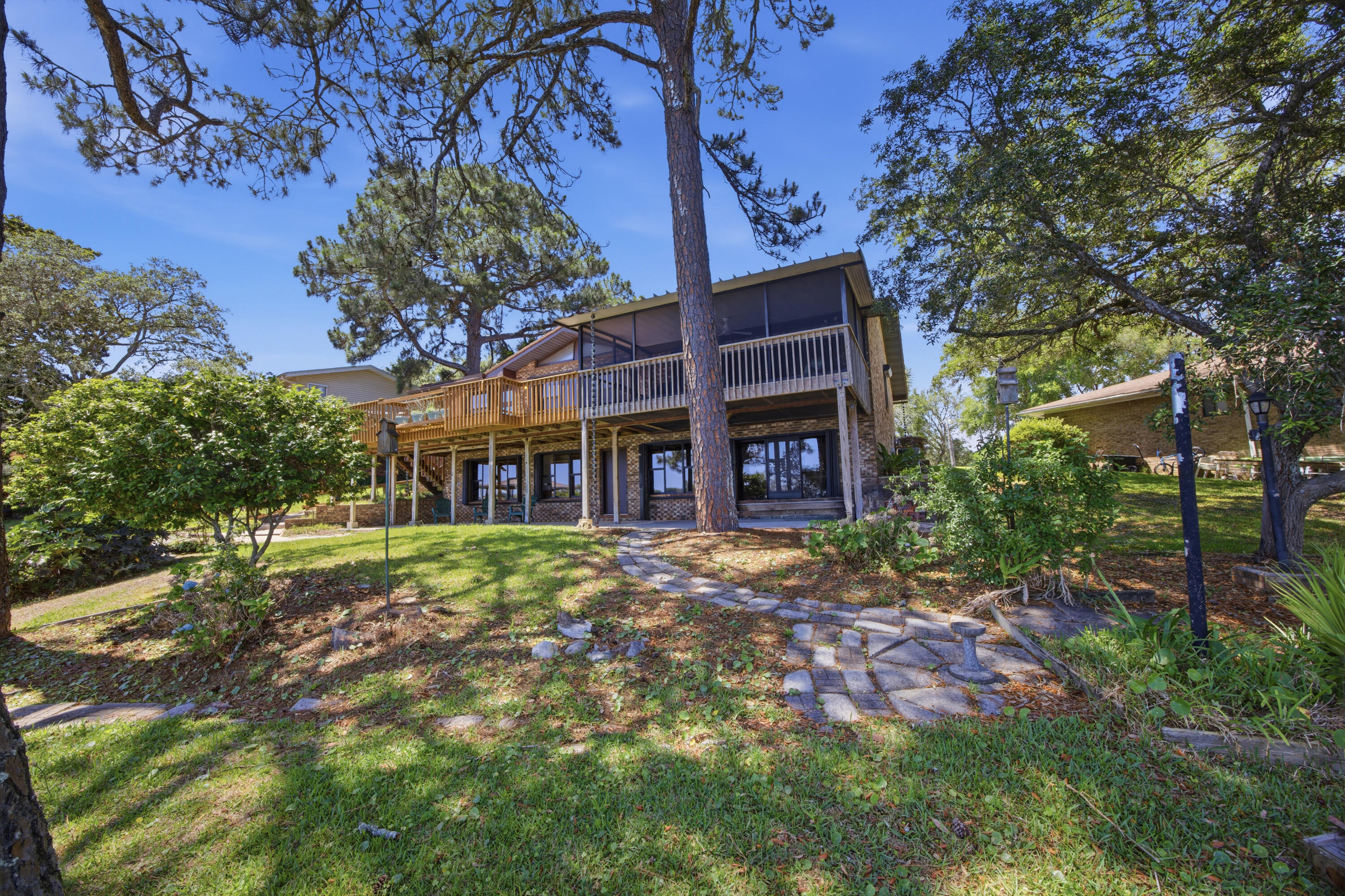 602 Cinco Terrace presents a rare waterfront opportunity with approximately 122 feet of protected bayou frontage while sitting well above the waterline, helping keep flood insurance costs significantly lower than many comparable waterfront properties. The home offers exceptional expansion potential with approximately 1,000 additional square feet ready to be incorporated into the existing footprint. A previously constructed and framed staircase location is already in place to seamlessly connect the upstairs living area to the unfinished lower level, creating a blank canvas for additional living space, guest quarters, an entertainment area, workshop, or custom design. Plumbing infrastructure for a future bathroom has already been planned with a drain line installed beneath the slab, simplifying future improvements without the need to disturb the concrete.

Inside, the home blends original character with modern updates. Fresh interior paint, updated lighting, and new luxury vinyl plank flooring throughout the living spaces, hallways, and bedrooms create a clean, contemporary feel while complementing the home's natural architectural features. Rich wood tones and stylish color-drenched interiors bring warmth and cohesion throughout the living spaces, creating an inviting waterfront atmosphere with timeless appeal. Popcorn ceilings were also removed throughout the home and garage in 2026, further enhancing the updated presentation.

Beyond the cosmetic improvements, the property has undergone substantial functional upgrades focused on durability, efficiency, and long-term peace of mind. Hurricane shutters were added to the windows, while the original asphalt roof was replaced with a metal shingle roofing system designed for longevity and enhanced weather resistance. In 2025, all exterior doors were upgraded to hurricane-rated doors with warranty documentation available. The kitchen was also refreshed with a full suite of Bosch appliances, pairing modern performance with the home's cohesive design aesthetic. Additional improvements include professionally cleaned and resealed grout in the bathrooms, kitchen, breakfast area, and office, along with updated ceiling fans and fixtures throughout the home.

Outdoor living was thoughtfully expanded to maximize the waterfront setting. The upper deck and lower concrete patio were widened to create more usable entertaining space, while a screened room was added to the upper deck to provide a comfortable year-round outdoor retreat overlooking the bayou. The lower level was further enhanced with expanded concrete flooring supported by CMU retaining walls, adding flexibility for storage, workshop space, hobbies, or future buildout potential. A dedicated photography darkroom also adds a unique creative element rarely found in comparable properties.

The mature landscaping creates a layered waterfront setting that blends native Florida vegetation with ornamental and edible plantings. Established live oaks, palms, palmettos, pine trees, ferns, agave, and American beautyberry provide natural texture and privacy throughout the grounds. Flowering additions including crepe myrtle, hydrangea, Rose of Sharon, fringe flower, amaryllis, caladium, fatsia, and crinum lilies introduce seasonal color and depth to the outdoor environment, while edible plantings such as banana trees, kumquat, fig, olive, and ginger further enhance the property's coastal garden atmosphere. A landscape irrigation system supports the grounds, and the home has also been converted from septic to county water and sewer for added convenience and reliability.

Positioned in Fort Walton Beach, the property offers convenient access to both Hurlburt Field and Eglin Air Force Base, making daily commutes efficient for active-duty military personnel, contractors, and civilian employees alike. White-sand Gulf beaches, waterfront dining, marinas, and the broader Emerald Coast lifestyle are all within close reach, allowing the property to balance privacy and waterfront living with accessibility to the area's most sought-after amenities.

602 Cinco Terrace delivers a compelling combination of protected waterfront frontage, elevation advantages, meaningful structural upgrades, future expansion flexibility, and a location that continues to remain highly desirable along the Emerald Coast. Buyers looking for a property that offers both immediate enjoyment and long-term potential will recognize the value, versatility, and lifestyle this waterfront home provides from the moment they arrive