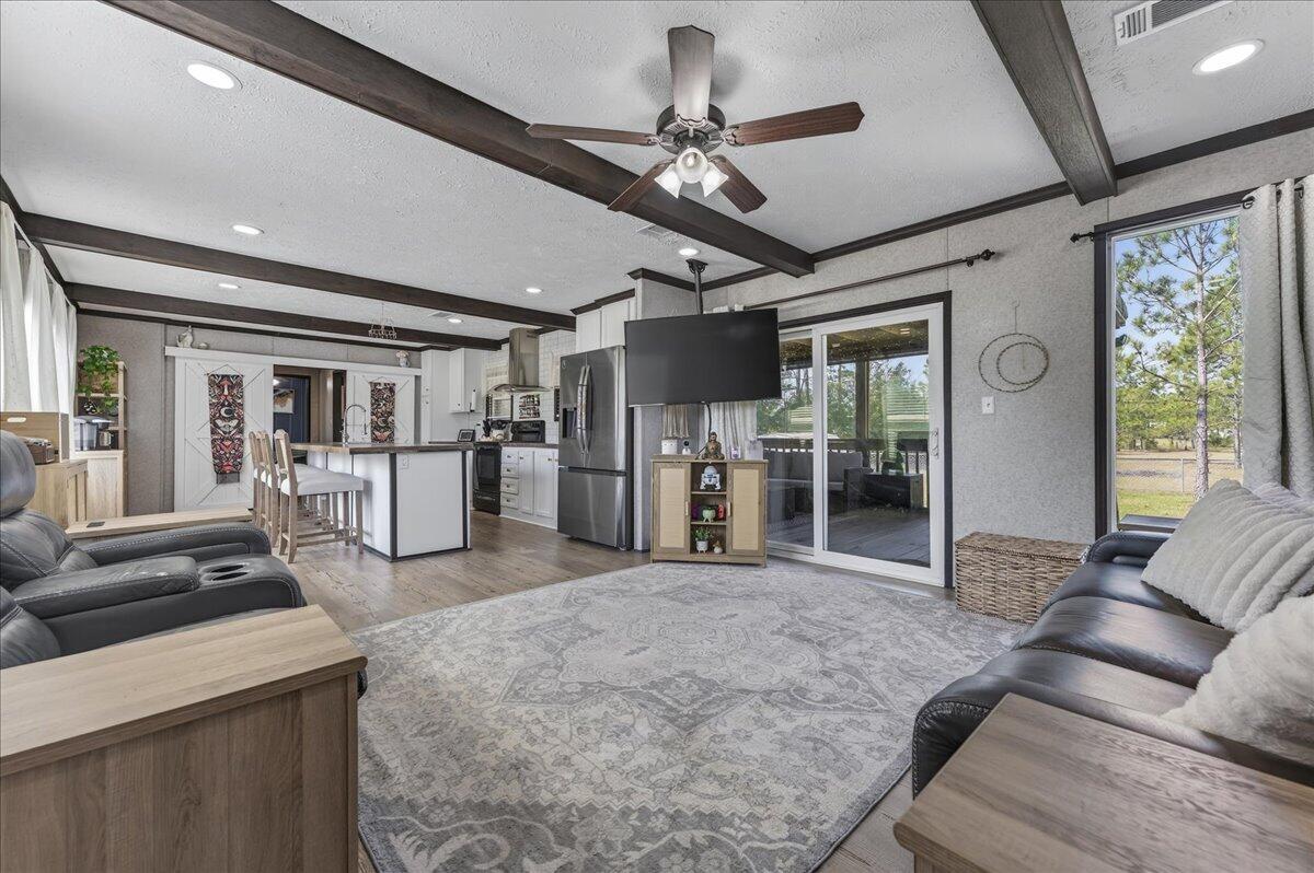 This home sits on 1.6 acres and is located just 25 minutes from Navarre Beach! Set on a quiet, well-maintained street and conveniently positioned just off Highway 87 with easy access to I-10, it offers a central location while still providing a peaceful, more private setting. The property features a spacious lot with mature pine trees and a fenced portion just off the home - great for pups! Inside, you'll find a neutral color palette, new 2024 flooring throughout, recessed lighting, and wood ceiling beams that add warmth and character. The open living and dining area creates an easy, functional flow for everyday living. The kitchen includes a large island with a breakfast bar along with ample cabinet and counter space. Just off the living room is a 30'8'' x 8'9'' screened-in porch that overl ooks the expansive lot, offering an outdoor living area. The split floor plan provides added privacy, with the primary suite featuring a walk-in closet and an en suite bathroom complete with double vanities, a garden tub, and a separate standing shower. Two additional bedrooms and a full bathroom with a tub/shower combo are located on the opposite side of the home. The property also includes a shed for extra storage. With acreage, mature trees, and a convenient drive to the beach and Pensacola, this home offers both space and convenience.