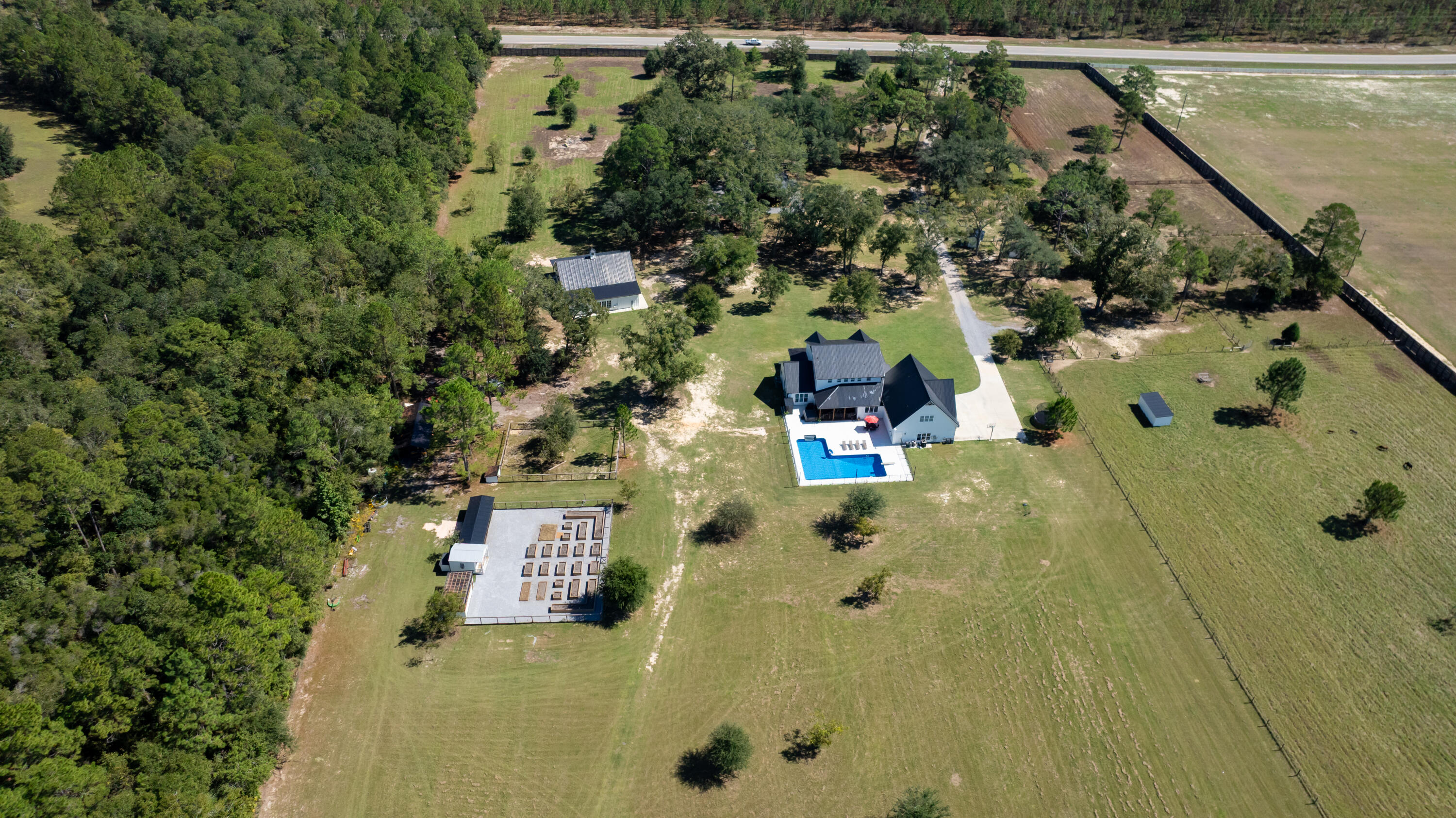 Modern farmhouse dreams meet next-level homestead living at 13796 State Hwy 81 in Ponce de Leon. Set behind full perimeter fencing on 20 pristine acres, this newly built estate delivers the rare balance of designer finishes, functional spaces, and true self-sufficient country living without sacrificing style. Inside the 5-bedroom, 4 full-bath, 2 half-bath farmhouse, clean lines and thoughtful details shine. The chef's kitchen anchors the home with white shaker cabinetry, under-cabinet lighting, custom vent hood, pot filler, butcher block countertops, and an oversized island that flows seamlessly into the open living space. A walk-in pantry with custom cabinetry and a dedicated coffee bar with beverage fridge elevates everyday living. The primary suite, tucked privately on the main level, feels like a retreat featuring a vaulted, beamed ceiling, abundant natural light, and a spa-inspired bath with freestanding soaking tub, glass-tiled rainfall shower, and a custom walk-in closet. Upstairs, two bedrooms offer ensuite baths and custom closets, while a bonus loft/bedroom above the 3-car garage includes its own AC, full bath, storage, and flexible space ideal for guests, a home office, or creative studio. Step outside and the lifestyle continues. The 3-car garage opens directly to a private resort-style patio complete with a 7.5-ft saltwater pool, hot tub, sauna, and cold plunge perfect for entertaining or unwinding at the end of the day. For equestrians, hobby farmers, or entrepreneurs, the 3,340-sq-ft barn is a standout feature, offering three horse stalls with automatic waterers and floor drains, an unfinished bath with plumbing and laundry hookups, and a climate-controlled upstairs office with LVP flooring and storage. Multiple access points, sliding barn doors, and ample equipment space make it as practical as it is impressive. The land itself is equally exceptional: five cleared pastures with water access, an 8-ft privacy fence across the front and down the left side, and a ½-acre stocked pond with floating dock. Additional amenities include pole and equipment barns, animal shelters, RV hookups, a treehouse with AC, chicken coop, greenhouse, raised garden beds, round pen, feed house, and pump house everything needed to live, work, and play on your own terms. This is more than a home, it's a turnkey Florida homestead designed for modern living, endless possibilities, and lasting legacy.