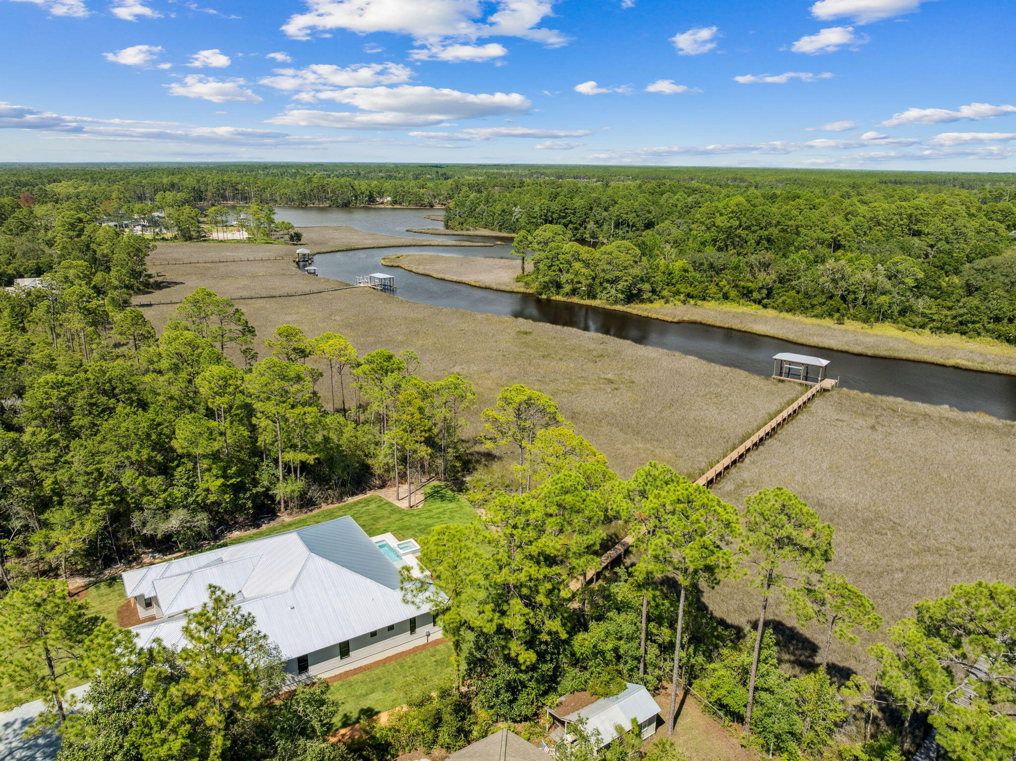 Welcome home to waterfront living on Eden Drive. This brand new, custom single-story home is situated on a private, half acre lot, including 4 bedrooms, 4.5 baths, a 3-car gar-age, boat dock and slip built for boats up to 32ft but with minor adjustments could accommodate a much larger vessel with boat draft access depth of 4ft. Delight in panoramic bayou views as you enter the home into a recessed foyer, the perfect space to feature artwork and welcome guests into your home. Designed with timeless finishes and thoughtful details, this residence features saddle brown stained oak floors throughout. The open concept living room boasts cypress accent coffered ceilings, a gas fireplace, and wet bar with wine and beverage center, creating the ideal entertainment space. Your stunning view is uninterrupted as you continue into the kitchen, showcasing an expansive Taj Mahal granite waterfall island with porcelain apron sink and antique gold bridge faucet. Preparing meals in this kitchen won't be a chore with a Butler's Pantry, Cafe 6-burner gas stove and double refrigerator/freezer. Just adjacent to the kitchen is a dedicated office space and additional storage with built-in desk and shelving. Step through full glass sliding doors to an expansive outdoor retreat. Enjoy your summer days and nights in your own backyard -- complete with covered patio, gas fireplace, outdoor kitchen, pool with sun-deck and hot tub, firepit, and a private dock and boathouse. With direct access to the In-tracoastal waterway and Choctawhatchee Bay, whether you plan to boat to dinner at The Bay or North Beach, or explore further to Destin Harbor and Crab Island, your boating options are endless right from your dock. The waterside master suite includes his and her closets, a soaking tub, and double shower for spa-like comfort. The three additional bedrooms offer ensuite bathrooms with custom tile finishes. The exterior of the home fea-tures artisan board siding, stucco accents, full glass steel front doors, and gas lanterns, portraying elevated Southern charm with modern luxury in Point Washington.