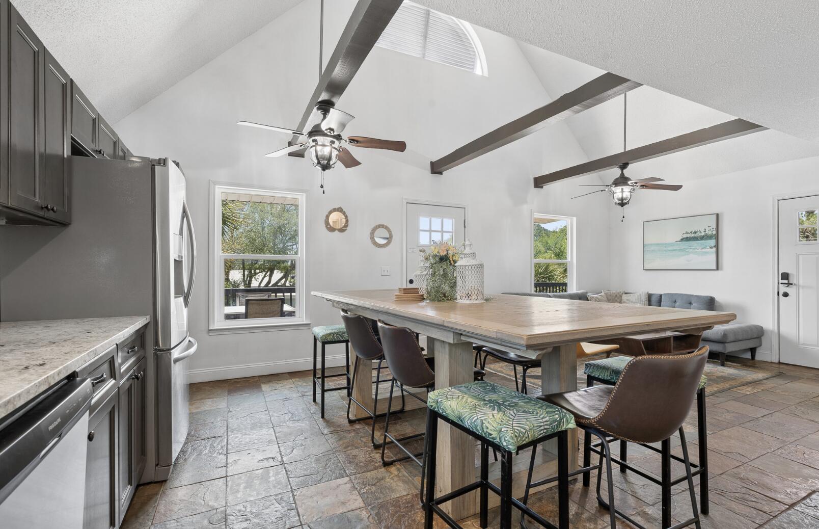 Turnkey and ready. Welcome to Dolphin Den -- a fully furnished 3BR/3BA coastal showpiece in the heart of Biltmore Beach, three blocks to sugar-white sand and 226 feet to the Dolphin Drive boat ramp. From the moment you arrive, the home's crisp white board-and-batten exterior, classic gabled roofline, and elevated wraparound deck capture the timeless Florida beach-cottage charm buyers dream about. Peek between the swaying palms and you'll catch glimpses of the bay just beyond -- your daily view from sunrise coffee to sunset cocktails.

The expansive elevated deck is the heart of outdoor living here: an alfresco dining set for four, a separate lounge area with cushioned seating, a grill ready for fresh catch, and room to entertain a crowd under the Gulf Coast sky. Inside: a main-floor king primary suite with double vanities and walk-in shower, an upstairs queen retreat, and a bunk room built for the kids. Open-concept living flows out to those bay views through every window. Stainless kitchen, smart TVs in every bedroom, 58'' living room screen, and a game room with two stand-up arcades.

Outside, mature palms and tropical landscaping frame a fully fenced corner lot with parking for four plus your boat, jet ski, or golf cart. Elevated construction means no flood insurance required -- along with no HOA, a 2020 roof, HVAC, and water heater, and a termite bond in place. The lower level beneath the home is plumbed and wired, ready to expand your square footage and your vision. Whether you're after a primary residence, a second home, or a proven short-term rental in one of PCB's most walkable beach neighborhoods -- Dolphin Den is the rare property that checks every box. Don't just buy a home. Buy the lifestyle.