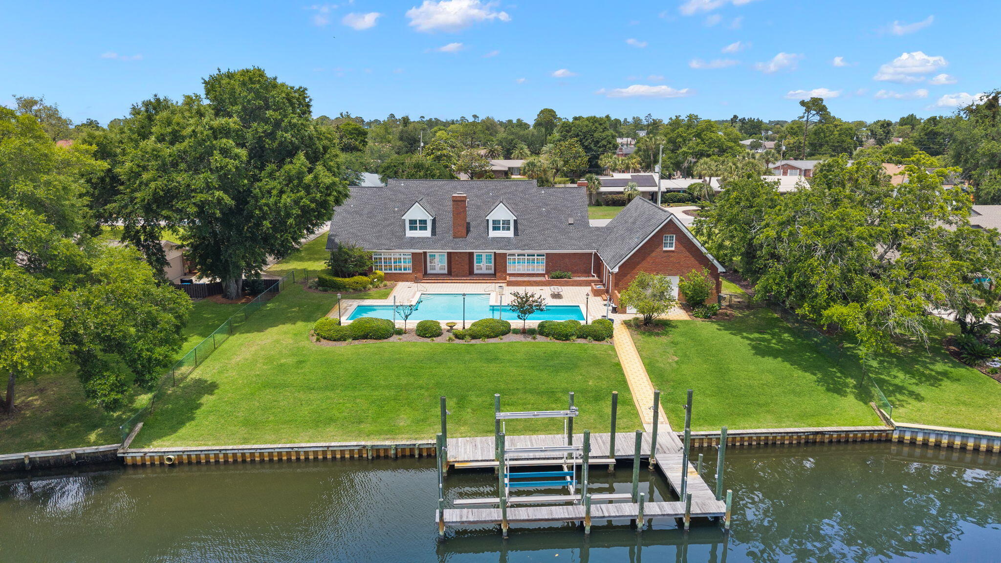 Nestled in the heart of Kings Point, one of Panama City's most storied and sought-after neighborhoods with NO HOA, this is an incredible WATERFRONT property where deep-water access, luxury amenities, and authentic community come together to make home. No HOA. This home is over 5,000 SF heated and cooled living space and has been designed for families who want everything within reach and ideal for those who want to truly live the lifestyle that waterfront living affords. 

Step out your door, onto your private dock and oversized pool. Deep-water access paired with a 10,000 lb. boat lift with walk boards in a 34'x14' slip means your vessel is ready the moment you are, and with just 6 nautical miles to the Gulf of America with no idle speed zones, a saltwater escape is never more than a short cruise away. This dock is designed and prepped to add a boat house cover so when the time comes, you're ready to make it happen. When staying home is on the agenda, the pool draws you in: designed with lap lanes for the swimmer who takes their mornings seriously and transforms effortlessly into the ultimate backyard centerpiece. It's equally suited for quiet Sunday floats and back yard gatherings with neighbors you're going to love! 

A charming brick exterior, a covered porch the length of the home and mature landscaping is what you're greeted with when you pull into your two-car garage. Inside, every space has been sized generously and designed with intention. Oversized bedrooms and walk-in closets offers a home feel like a true retreat. The primary suite is anchored on the main level by two closets that rival entire rooms. A gracious sitting room off the foyer sets the tone from the moment you arrive. The dedicated home office, complete with its own fireplace and built-in with custom millwork, is the kind of space that makes working remotely feel like a privilege. And upstairs there's a flex room that would be equally suited as a private fitness studio, playroom, or creative haven, adapting naturally as your life evolves. Above the garage, an additional fully outfitted 720 SF (not included in overall SF) theater room doubles beautifully as an independent mother-in-law suite. A full bath is also accessible from this area giving your guests the space they deserve or perfect for nights in a game room. Mahjong or poker anyone? 

The kitchen and living area are spacious and include exceptional views of the large pool, a pavered patio, mature landscaping and the waters leading into the Bay. The kitchen brings additional seating with an eat-in area and offers professional-grade appliances, a full-size wine cooler, double ovens-great for entertaining, cooktop with stainless range hood, ice maker, prep sink, and oversized walk-in pantry. The living area is anchored with a fireplace and flanked by two sets of French doors leading to the patio, pool and dock. The formal dining room is just off the kitchen and presented beautifully with a gorgeous chandelier and wallcovering. A convenient powder room for guests is located off the foyer in the center of the home. Upstairs, you'll find the flex room as well as two guest bedrooms with en-suite baths and multiple walk-in closets for each bedroom. This kind of space and room to spread out is rare in a home this size! 

Kings Point is the kind of community where people plant roots and stay. Walkable streets, mature canopy trees, and neighbors who wave...it's a pace of life that feels increasingly rare and genuinely worth savoring. The location is as practical as it is enviable: Publix and everyday conveniences are just minutes away. Coastal dining favorites in St. Andrews are just minutes away and the waterfront restaurants along St. Andrews Bay become part of your regular rhythm. Top-rated schools serve the area, and everything you love about coastal Florida living is right outside your door. Twenty minutes to the beach. Six nautical miles to the Gulf. A lifetime of living is found at 2806 Canal Drive.