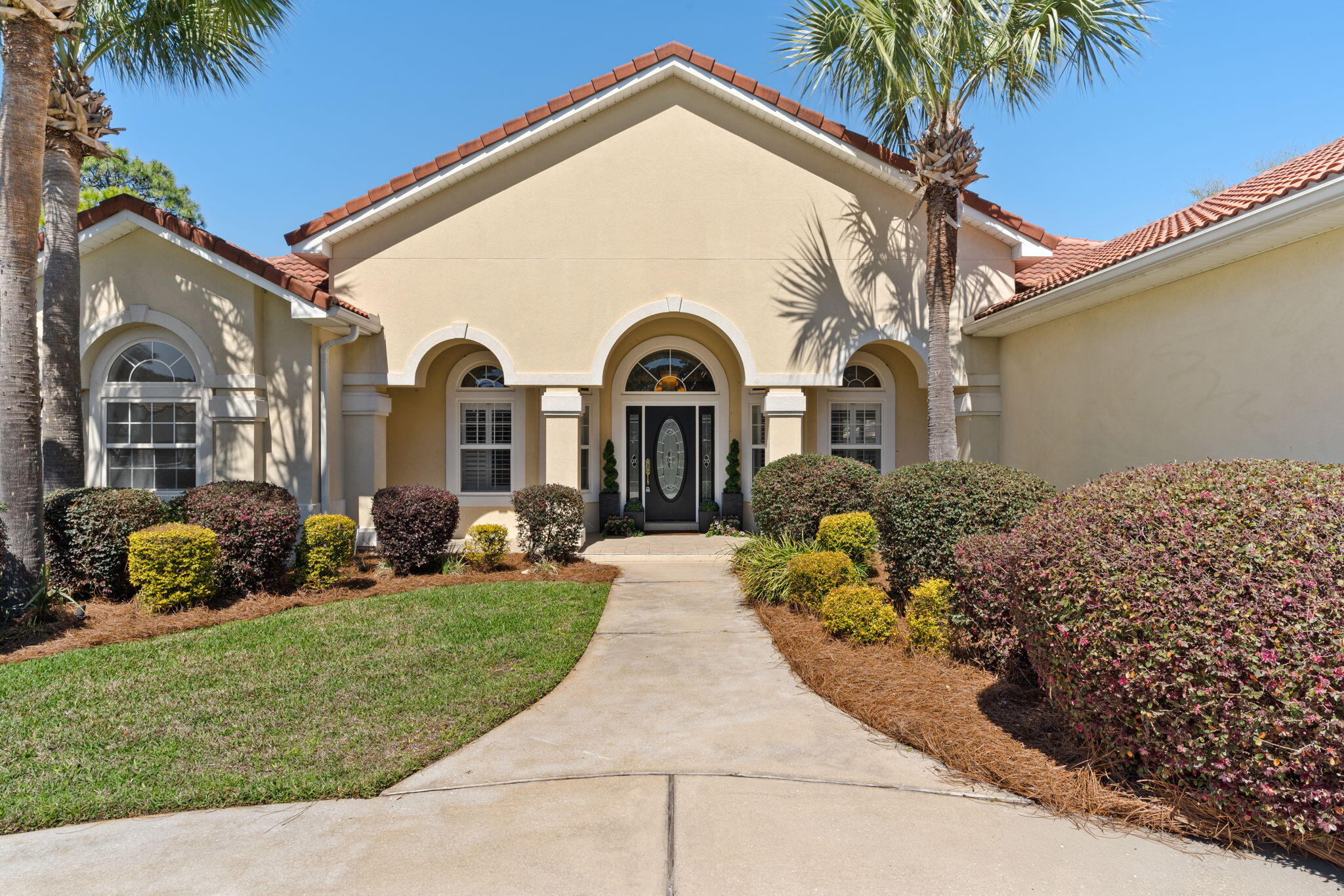 Step into effortless coastal living in this beautifully maintained 3-bedroom, 2.5-bath golf course home, complete with a flexible space ideal for a home office or additional living area, tucked inside the gated community of Emerald Bay. Perfectly positioned along the 5th fairway on a premium lot, this home is set back from the road with a circular driveway, offering both privacy and generous parking that's a rare find in the neighborhood. Inside, soaring 14-foot ceilings, tray details, arched openings, and plantation-shuttered windows create a bright, airy feel throughout. The thoughtfully designed layout flows with ease, offering both a formal living room and a second living area featuring a gas fireplace and custom built-ins that is ideal for both relaxing and entertaining.
 The kitchen is as functional as it is inviting, with granite countertops, stainless steel appliances, a prep island, under-cabinet lighting, tiled backsplash, and custom cabinetry for storage. The primary suite offers a true retreat, complete with a sitting area and private access to the covered lanai. The en suite bath features a jetted tub, separate shower, dual vanities, a private water closet, and two closets, including a walk-in. Designed with everyday comfort in mind, the home also includes a laundry room with utility sink and cabinetry, central vacuum throughout, and an oversized 26x20 garage with a side access door. Enjoy sweeping golf course views from nearly every room, as the main living areas and primary suite open seamlessly to the outdoor space. The expansive 43-foot screened lanai creates the perfect setting to unwind or entertain while overlooking the fairway, bridge, and tranquil water feature. Freshly painted and truly move-in ready, this home offers a turn-key opportunity in one of the area's most sought-after communities. Located in an X flood zone with a low HOA, Emerald Bay provides access to golf, a clubhouse, tennis courts, and a community pool--all just minutes from shopping, dining, and the beach.