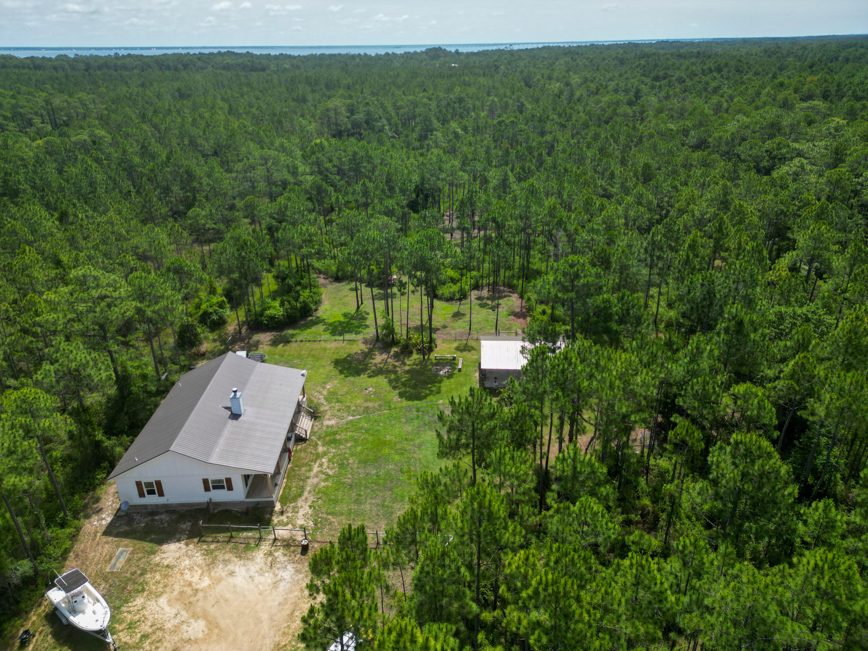 Priced $230,000 below value on appraisal and located on 10 peaceful acres in Santa Rosa Beach in South Walton County, this 3 bedroom 2 bathroom 1,870 SF secluded rustic home set well back from the road built in 2020 features a custom cypress wood kitchen island, copper sink, French doors, sprawling house-length front porch, walk-in pantry, freestanding tub, dual-head walk-in shower, and spacious walk-in master closet. plus the 10-acre property has a pole barn, a chicken pen, and a fenced yard.  Perfect for someone with pets or who loves animals as the surrounding deer and wildlife are plentiful.  This location is private and serene yet only minutes from the Gulf of Mexico, restaurants, and all the amenities that Northwest Florida has to offer.   SEE MORE...