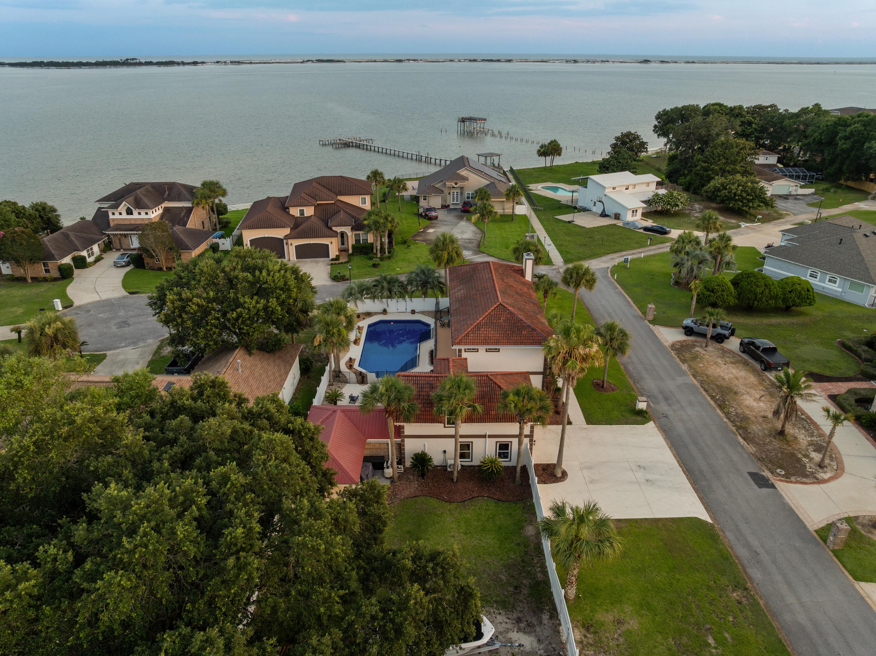 Experience the ultimate in coastal living with this stunning Mediterranean-style home offering breathtaking
Santa Rosa Sound views, 4 bedrooms, 3.5 bathrooms, 3,024 square feet of beautifully designed living space,
a resort-style 20' x 40' pool, and a private in-law suite. Perfectly situated just steps from the Santa Rosa
Sound, community dock, and beach access, this exceptional property blends luxury, comfort, and
convenience.
From the moment you enter, you'll be captivated by soaring ceilings, elegant tile flooring,
recessed lighting, and abundant natural light streaming through oversized architectural windows. The
spacious living room features dramatic vaulted ceilings, a cozy fireplace, and incredible water views,
creating the perfect setting for relaxing or entertaining.
The gourmet chef's kitchen is designed to impress with commercial-grade stainless steel appliances, a
professional gas range with vented hood, gorgeous quartz countertops, designer tile backsplash, custom
soft-close cabinetry, abundant storage, and a large center island ideal for gathering with family and friends.
The thoughtfully designed floor plan offers spacious bedrooms, generous living areas, and a fully equipped
in-law suite perfect for guests or multigenerational living. Step outside to your private backyard oasis
featuring an expansive pool, ample patio space, and tropical surroundings. Whether you're looking for a
primary residence or second home!