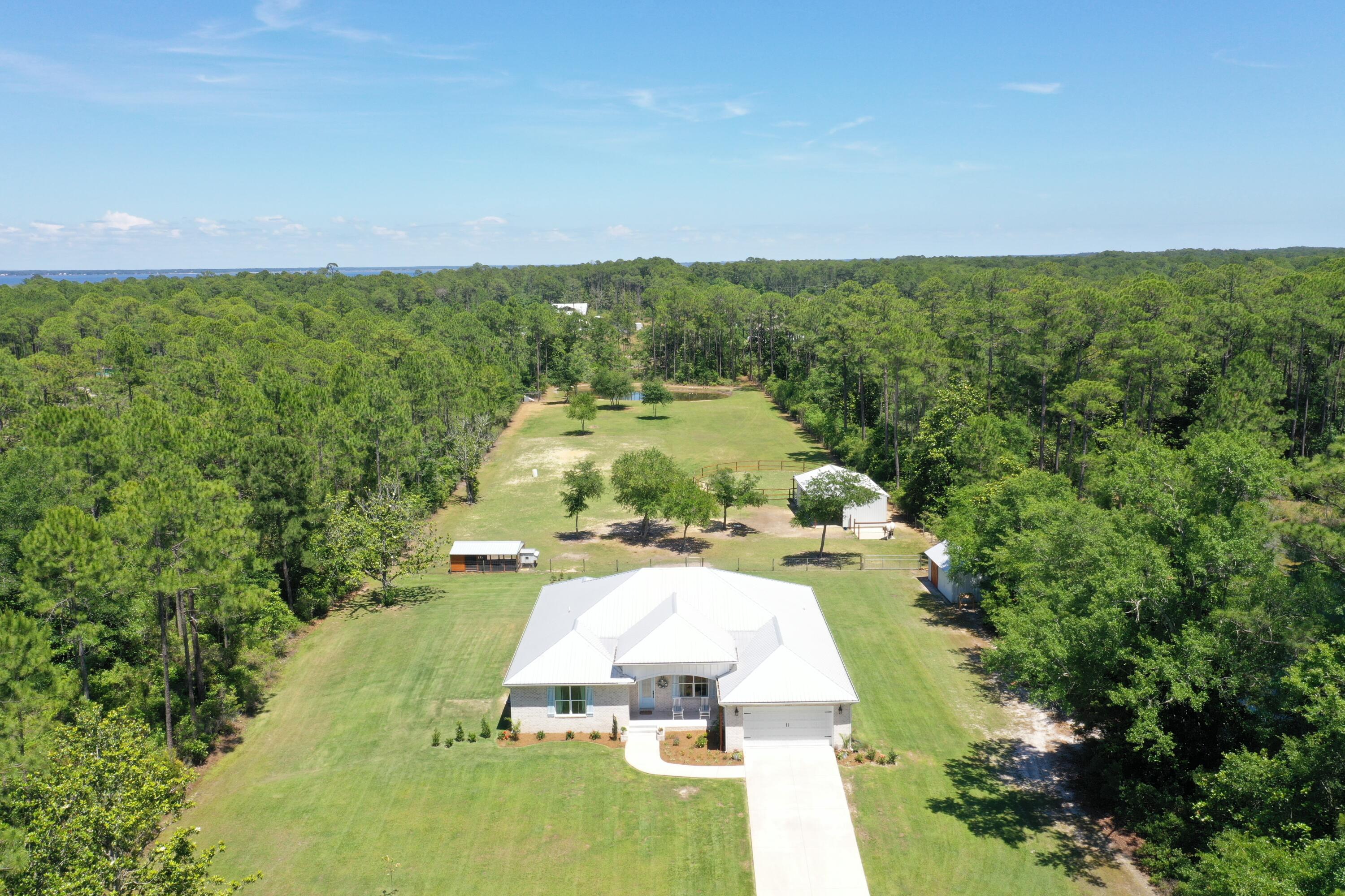 Experience coastal country living at its finest with this exceptional custom-built equestrian estate just minutes from the white sands beaches. Situated on nearly 5 private acres behind a gated entrance with automatic openers, this 2020-built property welcomes you home with a long shaded driveway, offering both privacy and a peaceful estate feel from the moment you arrive. blends modern luxury, durability, and fully equipped farm living.

Designed with quality construction in mind, the home features upgraded 2x6 exterior framing, a metal roof, impact-rated windows, whole-house water treatment system, and built on a concrete stem wall for long-term comfort and peace of mind. 
Inside the nearly 3,000sf home you'll find 5 spacious bedrooms, each with walk-in closets, and 3 full bathrooms finished with elegant quartz countertops throughout. The open-concept layout offers engineered wood flooring, oversized 8-foot doors throughout the home, and a beautifully designed kitchen complete with a walk-in pantry, generous entertaining space, and a stylish wine nook with built-in wine fridge. Outside there is an outdoor shower to rinse off after the day at the beach.

The property is perfectly suited for hobby farming, equestrian living, or simply enjoying the tranquility and beauty of the outdoors. Additional Features include:
3-stall horse barn with wash rack, tack room, automatic waterers and storage area (or change it into boat/recreation storage).
Chicken coop with enclosed run
Dedicated duck enclosure near the estate pond
Outdoor storage/yard building

Expansive open acreage with room to roam and fenced pasture.
Additional highlights include a 2-car garage, serene private pond, mature landscaping, and the rare combination of beach and bay proximity with functional farm amenities. The public boat launch is less than one mile away and the property offers ample space for parking boats and recreational vehicles.

This one-of-a-kind estate offers the ideal blend of luxury living, rural charm, and coastal convenience.

Owner is a L.R.E.A.