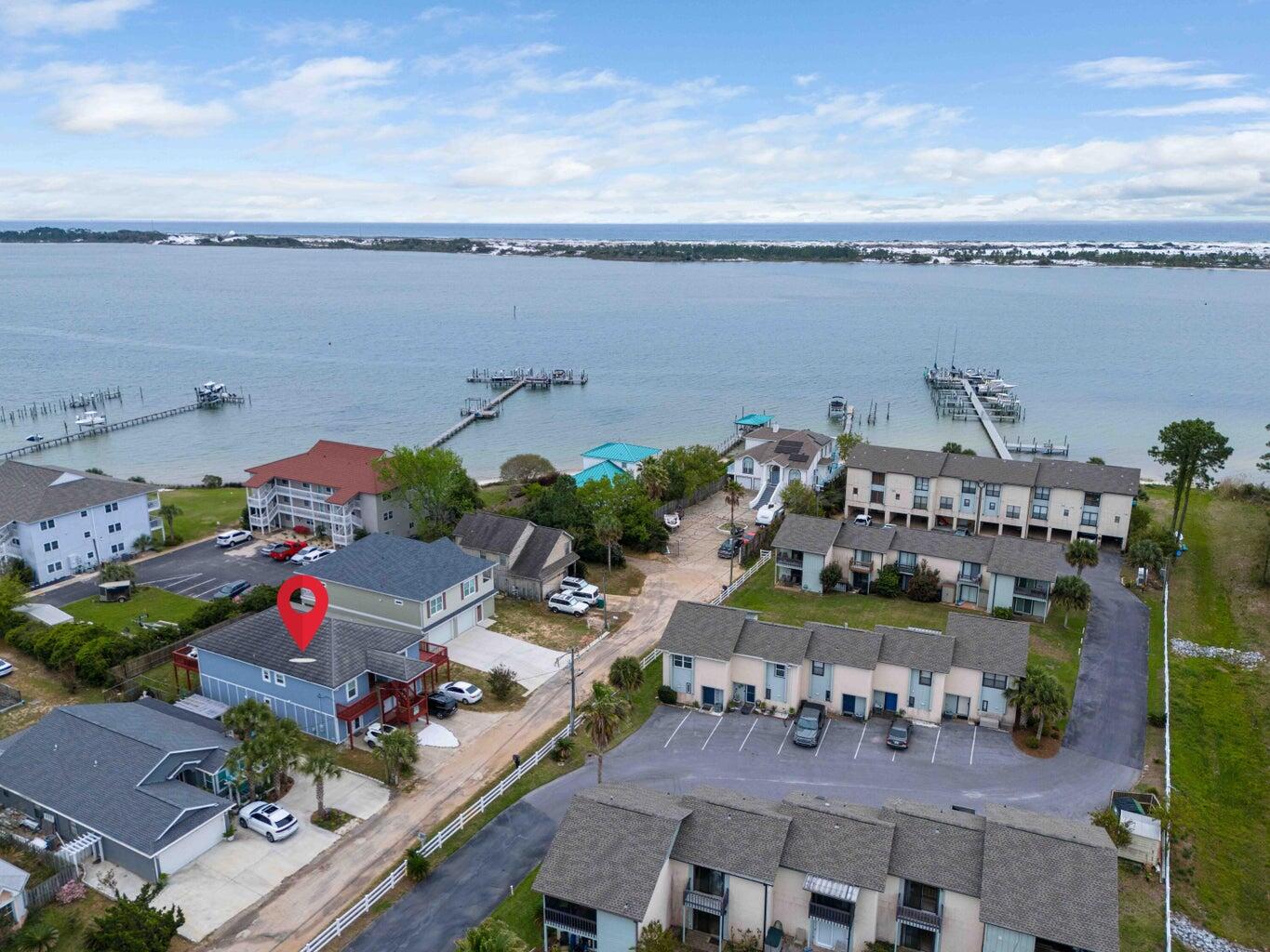 Coastal living at its finest! This Multi family remarkable property boasts a unique downstairs ADU with living room, full kitchen, bedroom and full bath, offering countless possibilities for extended family, guests, or rental income; This beautifully designed waterfront-view property offers approximately 2,863 square feet of open, airy living space plus a separate 950-square-foot apartment, making it perfect for extended family, guests, or rental income potential. Enjoy relaxing sound views from both the upper and lower decks, including a spacious wraparound deck ideal for morning coffee, sunset gatherings, or simply soaking in the coastal breeze. The fenced backyard, outdoor shower, and elevated construction, built 2 feet higher than required, add both convenience and peace of mind for beach living. The main home features 4 bedrooms and 4 baths, including three guest bedrooms with their own private baths. Neutral coastal-inspired gray tones, crown molding, and abundant natural light create a welcoming atmosphere throughout. The expansive living area flows seamlessly into the chef's kitchen, complete with stainless steel appliances, double ovens, breakfast bar seating, indirect lighting, decorative pendant fixtures, and five sliding glass doors that open to the surrounding decks and water views. The private apartment offers approximately 950 square feet with a large living area, open kitchen featuring butcher block countertops, dining nook, oversized primary bedroom, and a spacious walk-in closet, ideal for guests, multigenerational living, or income-producing opportunities. Additional highlights include a massive 3-car garage with plenty of room for vehicles, golf carts, boats, and beach gear; a large laundry room; floor-to-ceiling tiled showers; private water closets in the bathrooms; generous walk-in closets; durable metal roof; and a combination of tile and luxury vinyl plank flooring throughout, with carpet in select bedrooms for added comfort. Whether you're looking for a full-time residence, vacation retreat, or investment property, this coastal gem offers the space, flexibility, and water-view lifestyle you dream of living!