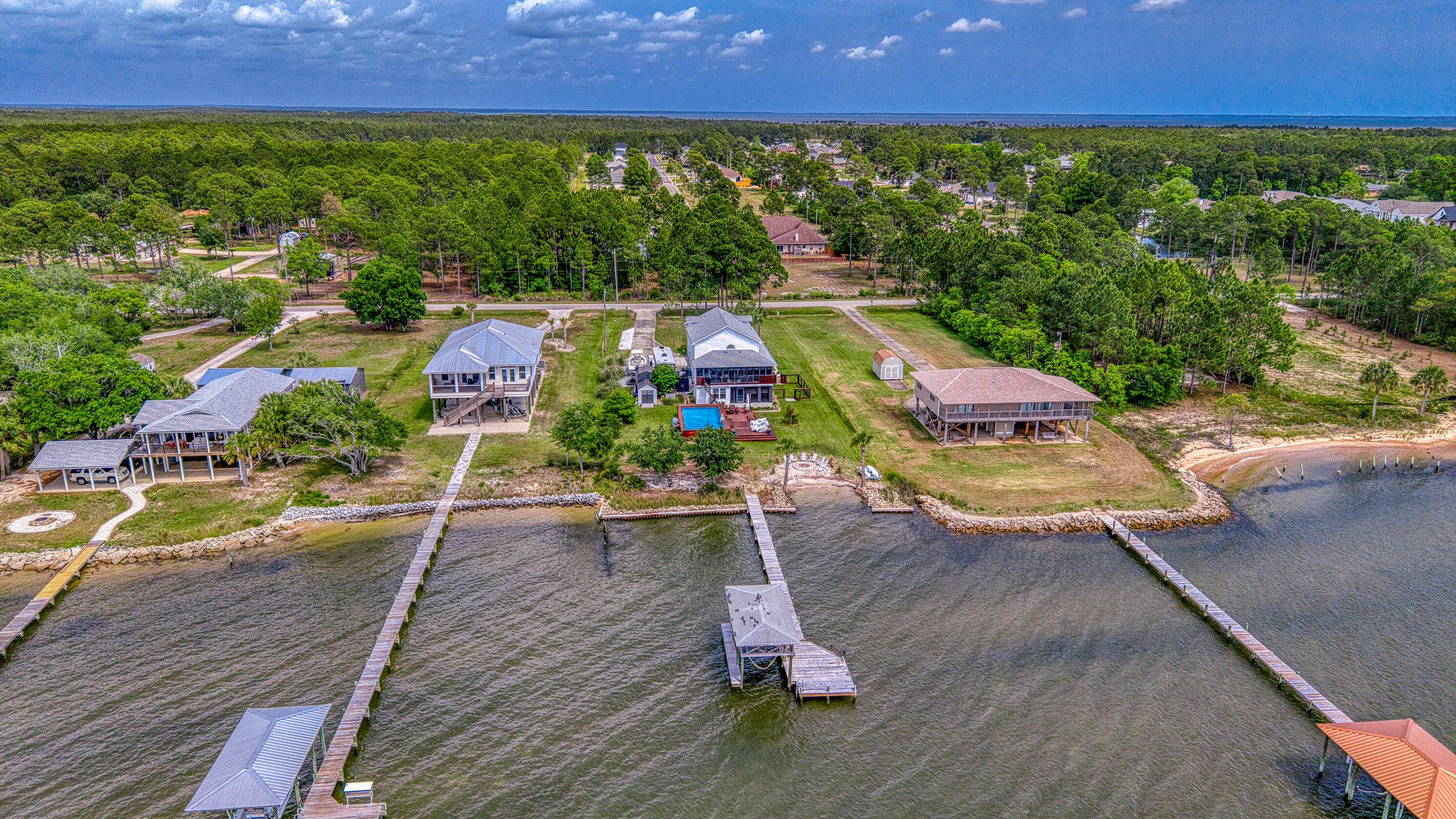 Bay Front home offering 3 bedrooms, 2.5 bathrooms, and a bonus mother-in-law suite. Experience refined coastal living in this beautifully reimagined luxury waterfront home of 2,034 square feet, all set on an expansive 0.81-acre lot with breathtaking west-facing views over Escambia Bay. Completely remodeled from top to bottom in 2023, this property offers relaxed elegance.

The main level showcases a thoughtfully expanded kitchen featuring new cabinetry, countertops, flooring, and appliances, along with a walk-in pantry and a stylish wet bar/beverage center. A newly added laundry room enhances convenience, while custom trim, fresh paint, solid wood interior doors, and updated finishes elevate the home's overall design. The open living spaces flow seamlessly to two screened-in porches-- to two screened-in porches--on both the main and lower levels--where you can take in stunning sunsets over the water.

The spacious primary and guest accommodations are complemented by a versatile lower-level bonus mother-in-law suite, complete with a kitchenette, full bath, and washer/dryer--ideal for guests, extended family, or additional living space. The lower level also includes a 2-car garage with generous storage.

Outdoors, this property truly shines. Enjoy direct waterfront access with a bulkhead, dock, boathouse, and boat lift equipped with electric and water. A walk-in beach area and stone fire pit create the perfect setting for evenings by the bay, while the above-ground saltwater pool with deck and grill area offers a private oasis for relaxing or entertaining. The expansive grounds also feature a new concrete driveway with a pickleball court and two RV sites with full hookups (electric, water, and sewer).

Additional upgrades include conversion from septic to city sewer with a grinder pump system, upgraded electrical service with new meter socket and breaker panels, and enclosure of the first floor for expanded functionality. With no HOA and excellent potential for short-term rental income.