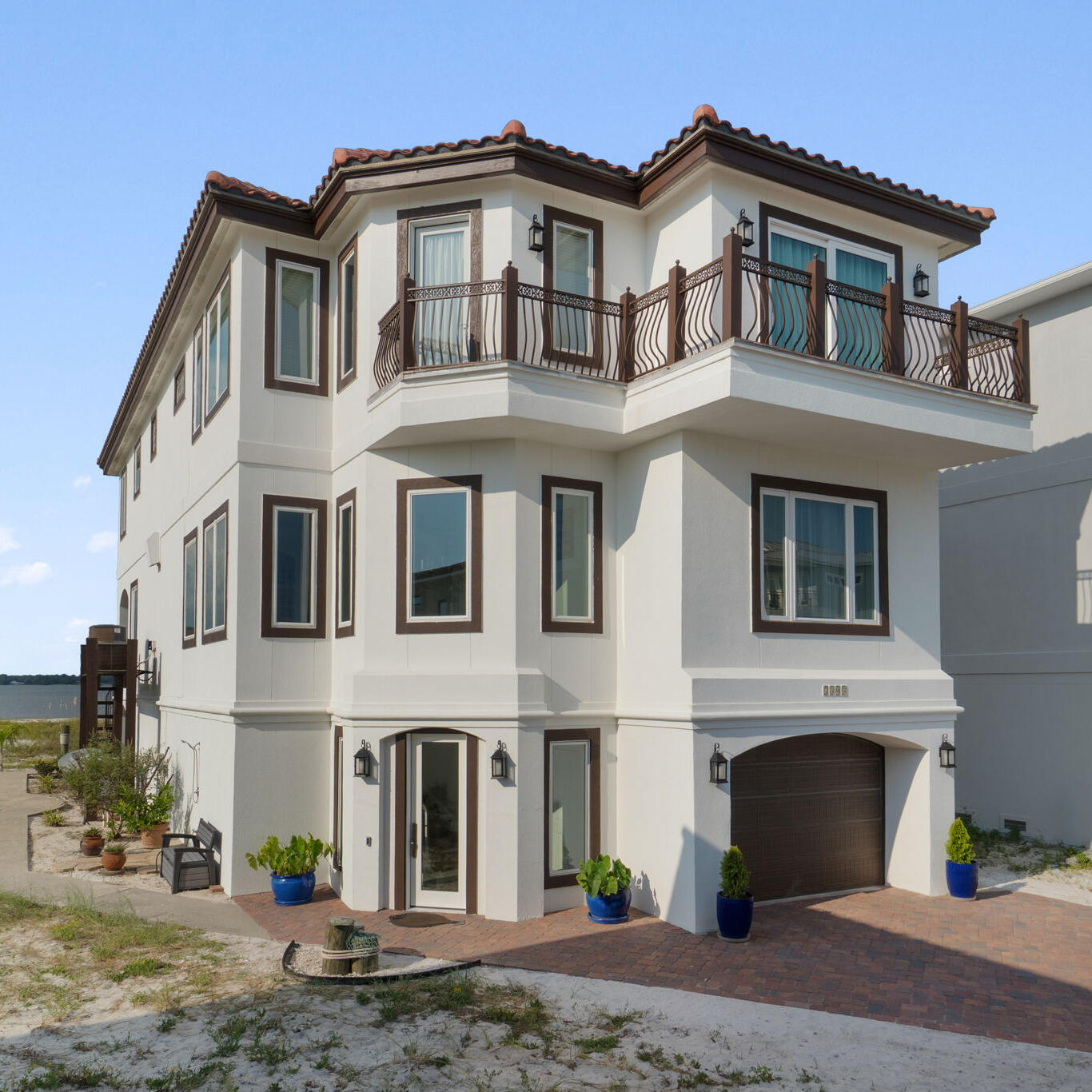 Exquisite Waterfront Residence in Sailmaker Cove. Step into a world of luxury and authenticity,  nestled within a prestigious gated community, the home offers unique character and essence.This custom-built residence  seamlessly blends timeless coastal design with elevated Mediterranean elegance. Forever views, surrounded by the serene landscape of Gulf Islands National Seashore. 
Upon arrival, the property makes an immediate impression with its elegant white stucco exterior and Spanish cement tile roof, complemented by a beautifully designed wrought iron balcony offering captivating views of the Gulf and it's pristine sugary beaches. Spanning over 3,794 square feet, this meticulously curated 4-bedroom, 5-bathroom home is designed to elevate your lifestyle and spirit. The first floor features an open-concept layout, perfect for gatherings, that effortlessly integrates into a chef's dream kitchen, adorned with high-end, custom solid wood cabinetry and stone countertops. Imagine dining while savoring breathtaking sunsets from the comfort of your home.
Additional highlights of the first floor include a spacious bedroom suite with a luxurious bath. Tiles and hard wood flooring and a host of subtle custom finishes thoughtfully designed throughout the home such as imported sinks, a stunning cement wall for showcasing your favorite wines, and exquisite 19th-century European stained glass above bedroom doors and throughout selected walls really showcase this spectacular home. The spacious primary suite on the second floor serves as a true retreat, boasting a cozy sitting area, custom built-ins, and a private balcony with breathtaking views of the Gulf. Two additional guest bedrooms, each with en-suite baths and picturesque views of the sound and national park, provide ample space for family or guests.The garage is equally impressive, with high ceilings and generous storage space, including an area designed for a golf cart.
The rear exterior of the home is perhaps its most enchanting feature, inviting you to relax or entertain at any time of day while being embraced by nature. Whether you prefer watching dolphins swim or enjoying a peaceful read, this unique setting promises to be a spectacular experience.Conveniently located just across from a tranquil, less-crowded beach. Take a short, scenic ride through the park to the vibrant Pensacola Beach for an array of dining and entertainment options. Sailmaker Cove provides a serene gated community experience, bordered by natural beauty, including the stunning Santa Rosa Sound.
Residents also have access to the refreshing community pool, making this property an ideal choice for a primary residence, vacation home, or a lucrative short-term rental opportunity. This home is truly a rare gem that will not disappoint!