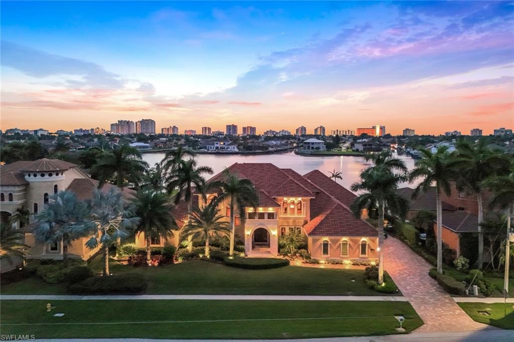 Offered at a level that would be extraordinarily difficult to replicate today, this grand-scale waterfront estate delivers unmatched craftsmanship, scale, and yacht-ready Gulf access on prestigious Smokehouse Bay. A commanding residence set on 141 feet of direct bay frontage, the home captures expansive southwest wide-water views and breathtaking sunsets, with deepwater, no-bridge access and a 30,000 lb lift—just minutes to the Gulf. Designed for grand living and entertaining, the estate showcases soaring two-story ceilings, a dramatic marble fireplace, and exquisite hand-crafted millwork throughout, reflecting a level of artistry and construction rarely achieved. The thoughtfully designed floor plan includes a chef’s kitchen with concealed appliances, butler’s pantry, walk-in pantry, custom wine room, private library, and a richly appointed home theater, creating a residence that is both impressive and highly functional. The primary suite is a true retreat, featuring a morning kitchen, spa-inspired bath with walk-through shower, dual water closets, and sweeping views over the pool to the bay. A grand spiral staircase or private elevator leads to two spacious upstairs en-suite bedrooms, each with its own private balcony overlooking the water, along with an expansive billiards lounge. Outdoor living is nothing short of spectacular, designed for grand-scale entertaining, highlighted by an infinity-edge pool and spa with cascading waterfall, expansive covered lanai, full summer kitchen, and a private guest casita with kitchenette. Lush tropical landscaping with swaying palms and fruit trees, enhance the sense of privacy and presence. A whole-house generator, impact windows and doors, 500-gallon propane system servicing the kitchen, fireplace, grill, and generator, and an epoxy-finished 3-car garage with custom built-ins complete the estate. A rare offering defined by architectural presence, artisan detail, and premier yacht-access waterfront living in one of Marco Island’s most coveted bayfront locations.
