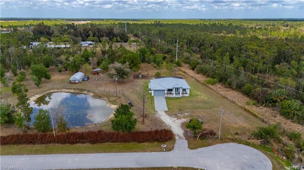 Privacy meets versatility on this 5.58-acre retreat bordering a 2,331-acre nature preserve. Located at the end of a quiet road, this bright 3BR + Office pool home features a separate luxury outbuilding ideal for a studio, gym, or entertainment hub. The outdoor oasis includes an expansive lanai with a pool and fridge, a wooden playset, a charming chicken coop and a pond. A true country sanctuary designed for entertaining and peaceful living. This home mirrors the perfection of a model home, featuring a soft neutral palette and soaring high ceilings that enhance the sense of space. Upgraded tile flooring flows seamlessly through the open-concept heart of the home, connecting the gourmet kitchen to the expansive living and dining areas. Designed for privacy, the split-bedroom floor plan offers a quiet retreat from the main social hubs.