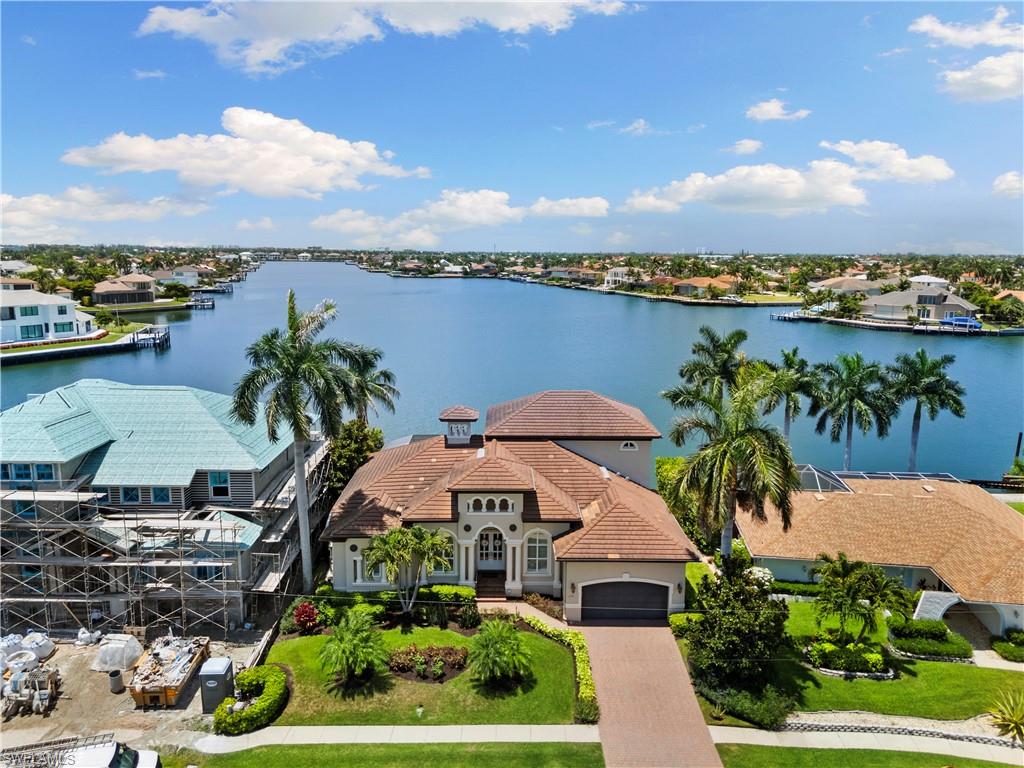 Step into an irresistible waterfront paradise with this jaw-dropping Divco-built 4 bedroom plus den, 3 bathroom masterclass of a home right in the heart of highly desirable Marco Island. The majestic water views from this home are downright SPECTACULAR; gaze upon a bay vista nearly a mile long and plenty wide. This home was custom designed to capitalize on its magnificent view - each room includes wonderful, impact-resistant windows so impeccable water views are always present. This includes every bedroom, with impact slider access to the outside. The second story in particular includes an outdoor balcony that delivers an unforgettable birds-eye view. Saunter on out to the pool area for more top-class waterfront experiences, including a heated pool and spa, pleasant sitting areas, and a boat dock that features a massive 20,000 pound boat lift (installed in 2025) and an additional PWC lift for kayaks that is rated for jetski weight as well; don't just look at the water, get right on it and enjoy some of the best boating life in the state of Florida - only a 15 minute out from the dock to the Gulf and the Ten Thousand Islands. It's not Island living without the beach, and access to Marco's iconic white sands is a mere half-mile away. Culinary enthusiasts rejoice, as this kitchen was updated in 2023 and features stunning cabinets and dazzling quartz countertops highlighted by unique elegant aqua patterns. Furthermore, this chef's delight of a kitchen includes a pantry, wine cooler, a newer refrigerator and microwave (2024), and newer dishwasher (2020). The home features pristine tile with warm wood flooring throughout. The primary suite serves as a private retreat, distinguished by darker wood floors, two spacious walk-in closets, and bathroom outfitted with separate vanities, separate jetted-tub and shower, and separate water closet. The home is well equipped with two HVAC systems and two hot water heaters. The home benefits from a slew of sensational updates, including, a newer pool heater (2023) and pump (2025), a coveted whole house generator (2020), and more; a full list of improvements is available. Come take a look at this waterfront paradise, as seeing is truly believing.