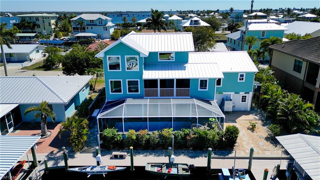 Custom Luxury Island Living! This stunning Matlacha home sits on 75ft of deep water intercoastal frontage and offers just as much outdoor living space as in! The fully screened ground level features a gorgeous, heated saltwater pool surrounded by a beautiful pavered pool deck and a huge outdoor living space. The ground level features a mother-in-law suite w/ full bath and kitchenette and a large workshop that would be any craftsman's dream! The back of the property is a water lover's dream complete with a dock that spans the entire length of the property, a 4k boatlift with custom aluminum roof, 2 personal watercraft boatlifts ideal for kayaks or a small boat, 220volt shore power and a fully functioning outdoor shower perfect for washing off the salt and sand after a day on the water!  As soon as you enter the main floor you can't help but notice the beautiful custom wood and metal details that are a signature of this home. Hand crafted nautical theme lacquered iron railings paired with cherry and maple handrails and cherry and maple stairs are seen throughout the interior of this beautiful home. The main level is truly spectacular, featuring soaring ceilings and an abundance of windows that let the natural light and beautiful views pour in! The main floor living room has huge picture windows that lend themselves to a great view down the canal and to Matlacha Pass. Dolphins, manatees and native seabird species are an everyday sight! The main living space is an open concept with Mexican Saltillo tiles throughout. The kitchen is a chef's dream complete with a double sink, chef sink, granite counters, a dual fuel stove, new Samsung refrigerator, new dishwasher, new microwave, beautiful, handcrafted cherry cabinets and an island bar with a custom cherry top. The main floor offers a large, screened porch with Brazilian walnut decking that really makes enjoying the outdoors from the upper level seamless! The main level hosts two spacious guest rooms which have natural cork floors. The master suite also resides on the main level featuring a large walk-in closet, full bath as well as access to the porch. As you make your way up the custom staircase to the second floor, you really start to experience the magnificence of this custom home! The second floor has THE VIEWS with the WOW FACTOR that all desire when looking for an island home!! The second floor has cherry flooring offering a large media loft, and ANOTHER balcony with Brazilian walnut decking! This home is loaded with many great upgrades including a 2025 standing seam metal roof, impact resistant windows and doors throughout, new Hardie plank siding, fire sprinkler system, central vacuum, zoned AC and 2 under home parking spots with remote control screens. Home is in the heart of Matlacha surrounded by world class fishing, pristine Gulf beaches and is within walking distance to waterfront restaurants, funky boutiques and galleries. Come see this home today and Start Living The Island Life!