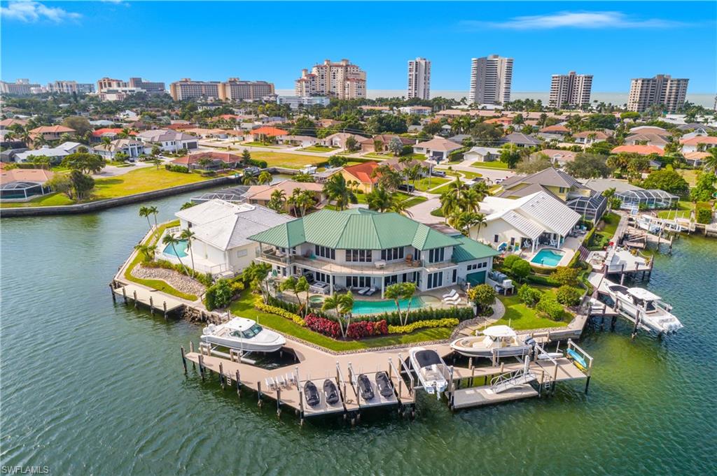 Live the dream - no Yacht Club membership required. This remarkable residence offers a full resort-style lifestyle with its own private marina designed for endless recreation, relaxation and adventure. Whether you're ready for a day on the water or simply soaking in the incredible views this property makes it effortless to enjoy paradise. For the boating enthusiast, choose from three boat lifts or two dual jet ski lifts for instant access to the bay. Prefer a slower pace? Slip into tranquility using the dedicated kayak and paddleboard lift and explore some of the most breathtaking waterways the island has to offer. When staying ashore, lounge beside the sparkling pool & spa surrounded by lush tropical landscaping - including your very own fruit trees. Once inside, the gourmet kitchen might tempt you to cancel those dinner reservations. Appointed with premium black granite, a Viking Professional Range and a cherry Sub-Zero refrigerator, it pairs elegance with culinary excellence. Custom cherry cabinetry, a kitchen island with built-in sink and microwave, plus a walk-in pantry with an additional sink provide both beauty and function. Prefer cooking outdoors? The fully equipped outdoor kitchen complete with pizza oven makes entertaining unforgettable. This magnificent home was built prioritizing family accommodations & entertainment to its fullest. Gorgeous dining area has wine cooler and wet bar, and the spacious living room has a warm & inviting gas fireplace. Other luxuries include an elevator, a central interior & exterior music system. Two oversized master suites, and three additional bedrooms + an extra storage room. Incredible water views from the expansive glass second level loft with piano and extra living space. The marble staircase flows throughout the foyer great room, dining area, and kitchen. Gigantic 4-car garage with endless storage including loft, and an adjacent utility-workshop room which must be seen. Garage also has a rear roll-up door for easy egress to the back of the property. The whole home generator provides peace of mind and uninterrupted luxury living. Enjoy evenings around the firepit while admiring the oversized pool, spa and deck area. Renowned Resident's Beach, just one of the island's treasures is just a quick golf cart ride away. This isn't just a home - it's a total lifestyle. A sanctuary of luxury, adventure and endless coastal living.