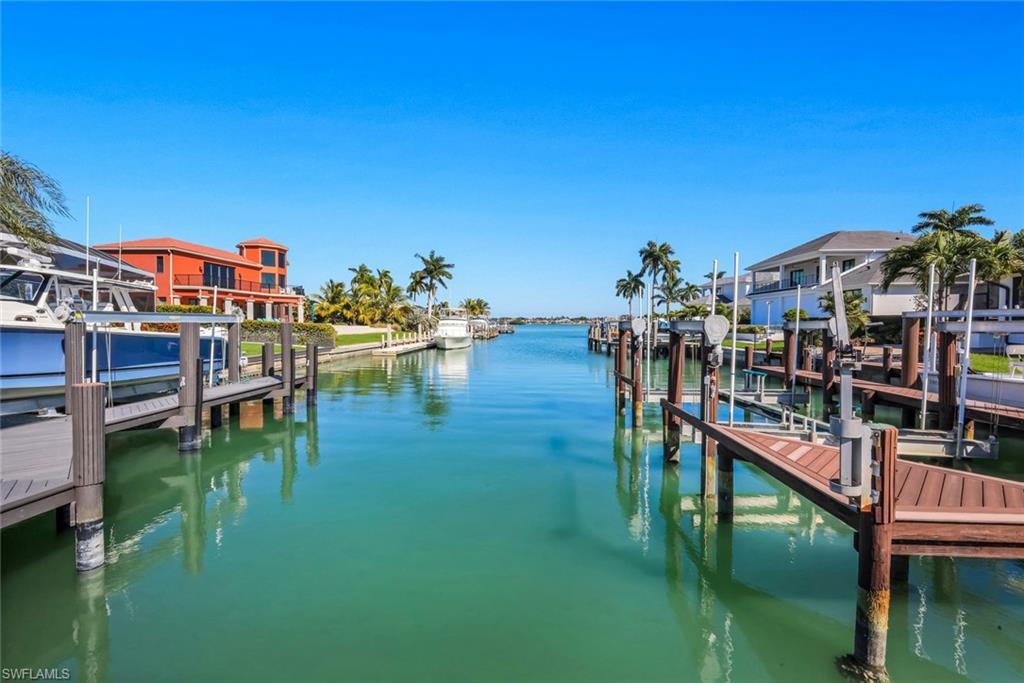 No expense was spared in the creation of this custom luxury residence, ideally positioned within the exclusive Estates of Marco Island. The home enjoys partial views across Roberts Bay and offers quick, direct boating access to Caxambas Pass and the Gulf, setting the stage for an exceptional coastal lifestyle. From the moment you enter, exquisite finishes, one-of-a-kind custom tile work, and carefully curated architectural details reflect a commitment to craftsmanship and elevated design throughout.

Built in 2017, the residence offers approximately 3,467 square feet under air in the main living areas, complemented by a separately conditioned hobby room that adds remarkable flexibility. The open floor plan is anchored by a spacious great room that seamlessly connects the kitchen, living area, breakfast nook, and open den, creating a layout equally suited for everyday living and entertaining. Vaulted ceilings soaring up to 21 feet and eight-foot solid core doors enhance the sense of scale and light.

The kitchen blends high-end performance with understated elegance, featuring a JennAir cooktop and double ovens, a newer Whirlpool refrigerator, and a hidden walk-in pantry concealed behind cabinetry for a clean, uninterrupted aesthetic. The home includes two true primary suites, thoughtfully separated for privacy, along with additional guest accommodations. Pocket doors allow the guest wing to be closed off from the main living areas, and the guest bath doubles as a pool bath for added convenience. A 456-square-foot air-conditioned hobby room with its own entrance and dedicated HVAC system offers the potential for a mother-in-law suite, caregiver quarters, fitness studio, or additional bedroom.

Comfort and reliability are built into every aspect of the home, with two main HVAC systems plus a separate system for the hobby room, a whole-house generator, two tankless water heaters, hurricane shutters at the rear, remote-controlled shade screens, a security system, and integrated Sonos audio throughout. A four-car garage with epoxy flooring provides ample space for vehicles and storage, while paver walkways along the side of the home create easy access to the waterfront.

For boating enthusiasts, the property delivers exceptional infrastructure. A newer 148-foot seawall, completed in 2015, anchors the expansive water frontage, while a custom dock system is equipped with both a 58,000-pound lift and a 12,000-pound lift. The generous paver dock area allows for waterfront entertaining and effortless access to the water, seamlessly extending the outdoor living experience beyond the pool deck and lanai.

With no history of water intrusion and proactive flood panels already installed, this residence combines luxury, foresight, and functionality. It is a rare opportunity to own a meticulously designed waterfront home that offers both refined living and immediate access to the open waters that define the Marco Island lifestyle.