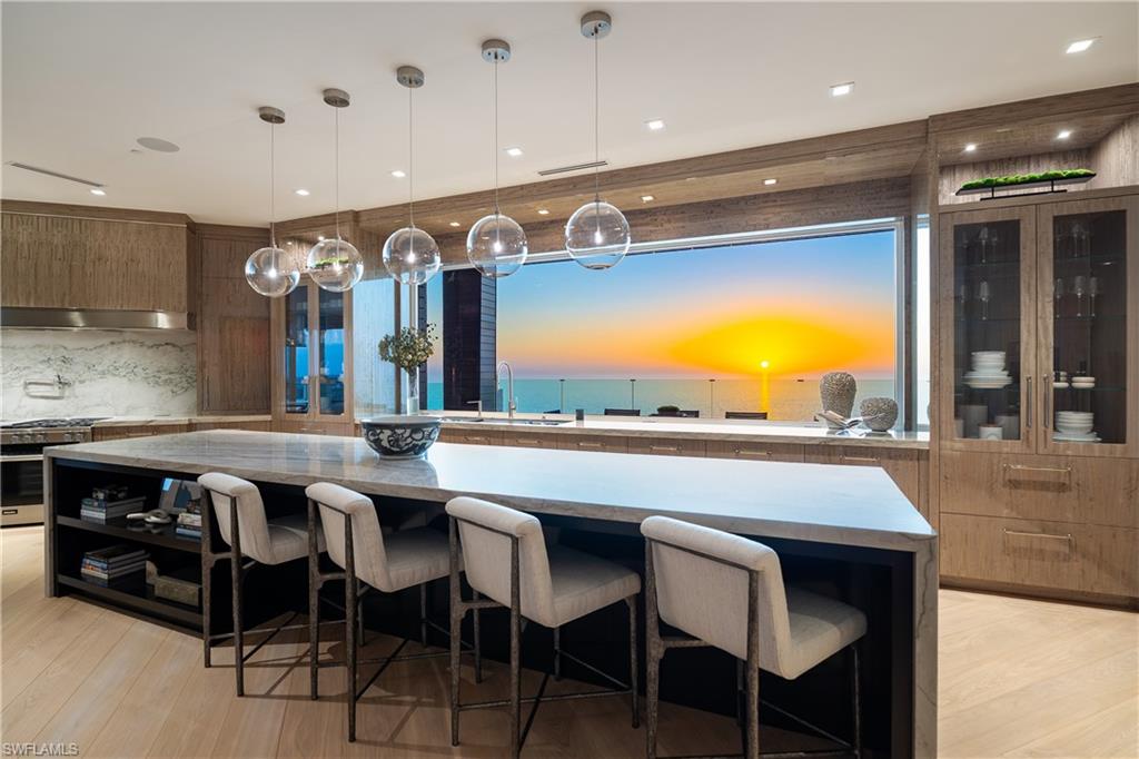 Uncompromising in quality and truly one of a kind, this extraordinary penthouse offers a masterfully designed layout with four distinct corners of covered and open air outdoor living, capturing breathtaking 360 degree views across all of Naples. Blending the ease of condominium living with the privacy of a single family home, the residence features an enclosed private three car garage and secure elevator access that opens directly into your own private foyer. Encompassing nearly 13,000 square feet of refined interiors, the thoughtfully designed floor plan includes five guest suites, a dedicated office, and an expansive primary wing perfectly suited to accommodate a variety of lifestyles while delivering the highest level of comfort and sophistication. Every detail has been meticulously curated, from the herringbone oak flooring and custom eucalyptus cabinetry to reeded accent walls and statement lighting throughout. The gulf facing kitchen is a true showpiece, highlighted by a dramatic 12 foot picture window, an oversized center island with a thick quartzite waterfall edge and full height backsplash, and top tier
appliances all seamlessly connecting to the southwest facing terraces. Here, a fully equipped summer kitchen and bar create an unparalleled setting for entertaining against a backdrop of sweeping coastline views. The primary wing is a private sanctuary unlike any other, offering dual covered terraces, an outdoor hot tub, a spacious bedroom retreat, bespoke walk in closets, a sauna, a fitness room, and dual spa inspired baths, including a freestanding soaking tub perfectly positioned to take in endless water views. Among the most exceptional penthouses in Naples, this residence represents a rare opportunity to own a fully reimagined architectural statement where striking design is rivaled only by the panoramic beauty of the Gulf and beyond.