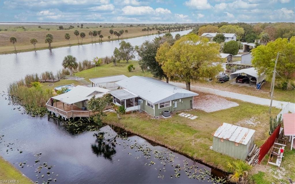 Enjoy the best of Lakeport waterfront living!  This great peninsula location offers two scenic canals, with the Hoover Dike to the south and great Rim Canal frontage.  This charming 2 bed / 2 bath home features Spanish tile flooring, built~in storage, French doors to a screened porch and a private covered fishing deck.  All under the comfort of a shaded waterfront lot.  Launch your boat just ¼ mile away at Harney Pond for quick access to Lake Okeechobee—perfect fisherman’s dream!  Outdoors, you’ll love the fishing deck directly on the rim canal, fish cleaning station, an in-ground swimming pool, an additional outbuilding with laundry area and a well equipped workshop or hobby space. Enjoy the private kayak/canoe launch, public water and easy access to Hwy 78 for anyone with a commute to Moore Haven or Okeechobee.  This property offers both relaxation and recreation in one special package!  Don't miss out on this one, make your appointment today!