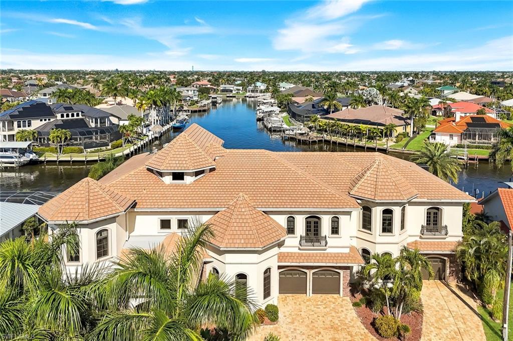 Over-the-top luxury and timeless elegance define this extraordinary custom-built estate offering nearly 9,000 square feet of refined living to include 8 bedrooms, 6 full bathrooms and 3 half baths. Some of the finest deep-water, direct Gulf access in all of Southwest Florida. With 150 feet of intersecting canal frontage, the property features a newer dock designed to accommodate a 100’+ mega yacht, a lift for a 35’ vessel, and ample room for additional watercraft and toys.  From the moment you arrive, the dramatic entry and sweeping grand spiral staircase create a truly unforgettable first impression. The main level is designed for both grand entertaining and everyday comfort, featuring a formal dining room, an expansive family room with a stunning full bar, and a chef’s kitchen outfitted with Sub-Zero and Wolf appliances, including a gas range, oversized island, double wine chillers, RO system under the sink, and a whole-house water softener. A luxurious guest primary suite and additional en-suite bedrooms complete the first floor.  An elevator or the elegant staircase leads to the second level, showcasing an impressive entertainment lounge, a private executive office with a hidden, climate-controlled wine room, a glass-enclosed fitness center overlooking the intersecting canals, and an expansive primary retreat with its own laundry. Multiple additional guest suites—including an ideal in-law configuration—are also located on this level. Notably, the home features four hidden doors and secret rooms, adding a rare and intriguing architectural element throughout.  The third level offers a second office or flex space that opens to an enormous balcony with breathtaking panoramic views. Outdoors, the residence truly becomes a private resort with a spectacular pool featuring a water slide and waterfall, complemented by a fully equipped outdoor kitchen with a Fire Magic Echelon grill, side burner, abundant storage, and prep space—perfect for entertaining waterfront guests.  Additional highlights include an oversized three-car garage with ceiling height and layout suitable for vehicle lifts to accommodate up to six cars, five zoned HVAC systems for optimal climate control, and a dedicated cooling system for the wine room. The home received a new roof and dock repairs following Hurricane Ian and experienced no flooding. This remarkable estate is a rare offering—an entertainer’s dream and one of the most impressive waterfront homes available in Southwest Florida.