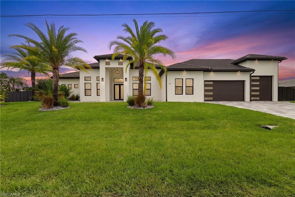 Set on an oversized corner lot, this exceptional custom residence delivers the space, craftsmanship, and resort-style amenities that define luxury Southwest Florida living. Offering 4 bedrooms, 3.5 bathrooms, a private office, den, exercise room, and generous storage, the home is thoughtfully designed for comfortable everyday living, working from home, and effortless entertaining.
A true showpiece of the property is the remarkably spacious RV and boat garage—a rare and highly desirable feature in Cape Coral. With epoxy flooring, extensive custom cabinetry, and room for an RV, boat, recreational vehicles, or a prized car collection, this versatile space is ideal for those who refuse to compromise on storage or lifestyle.
Inside, soaring volume ceilings and elegant tray ceilings create an impressive sense of openness, while impact-rated sliders and doors fill the home with natural light. Beautiful 36-inch tile flows throughout, complemented by upgraded lighting, fixtures, ceiling fans, and recessed lighting that add warmth and sophistication.
At the heart of the home, the expansive kitchen pairs style with functionality. Quartz countertops and backsplash, upgraded stainless-steel appliances, abundant cabinetry, and generous prep and gathering space make it equally suited for quiet evenings or entertaining a crowd.  The private owner’s suite is a luxurious retreat featuring custom walk-in closets with wood shelving and a spa-inspired bathroom with dual vanities, an oversized walk-in shower, soaking tub, upgraded mirrors, and quartz finishes. A second primary suite provides exceptional comfort and privacy with its own walk-in closet, spacious shower, and beautifully appointed bath—perfect for extended family or overnight guests.
Custom glass doors distinguish the private home office, while the separate den, exercise room, and dedicated storage room offer tremendous flexibility. 
Step outside and experience your own private retreat. The approximately 16-by-35-foot saltwater pool features a beach entry, spa, heater, and screened enclosure. An expansive paver deck offers abundant room for sunbathing, outdoor dining, and entertaining. The outdoor kitchen includes an installed sink and space for a gas grill and refrigerator, creating the perfect setting for enjoying Florida living.
The fully fenced backyard continues to impress with a custom sport court, lush landscaping, mature palms, concrete landscape curbing, and irrigation. A tile roof, impact-resistant windows and doors, an expansive paver driveway, and professionally designed landscaping complete the home’s striking curb appeal.
Conveniently located near shopping, dining, and everyday amenities, this extraordinary property offers a combination of luxury, versatility, and recreational space that is increasingly difficult to find. For RV owners, boating enthusiasts, car collectors, or anyone seeking a truly distinctive Cape Coral home, this property stands in a class of its own.
