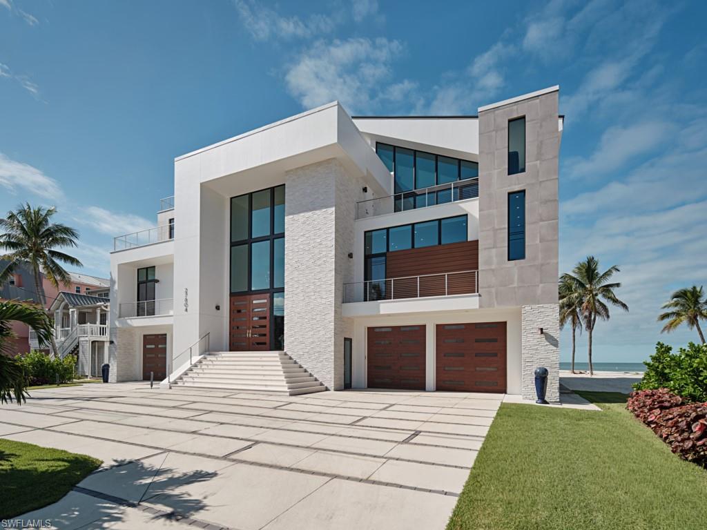 There are homes with views, and then there are homes that become the view—places where the horizon feels close enough to touch and each day ends in a watercolor sunset. 27804 Hickory Blvd is one of those rare coastal sanctuaries, designed with intention, crafted with obsession, and lived in with a sense of quiet exclusivity. Set along a wide, unbroken expanse of Bonita Beach, this modern Gulf-front estate rises with sculptural confidence. Clean lines, soaring glass, and bold geometry speak to residential designer Rich Guzman’s signature style, where art meets application, and every space borrows from the beauty beyond its walls. Built by the award-winning team at Potter Homes and finished under the direction of Adelyn Charles Interiors, the residence feels both architecturally significant and intimately livable. Inside, natural light pours through two stories of glass, moving across warm wood, curated textures, and a palette inspired by the sand and sea. The grand staircase—part engineering feat, part sculpture—anchors the home with quiet drama. The kitchen, soft in tone yet unapologetically high-performance, invites long family meals that curate the conversations that truly matter. The main living level opens wide to the Gulf, dissolving the line between indoors and out. Upstairs, the primary suite claims a corner of the world most people will only dream of, sunrise light at your back and a 180-degree sweep of ocean at your feet. Mornings here are slow and unhurried; evenings unfold with the kind of sunsets that reset your pulse and refocus your mind. The residence’s guest suites offer privacy and comfort, ensuring friends and family feel at home without disturbing your own sense of retreat. Expansive terraces, a rooftop vantage point, and thoughtfully designed outdoor living spaces create a lifestyle that moves fluidly from beach to balcony to breezy nights around the fire. And beneath its beauty, the home is built with a level of strength and resilience—storm-engineered, elevated, and future-proofed for generations. For the discerning buyer seeking a coastal escape—a place to trade snow for shoreline, intensity for ease—this residence provides more than sunshine. It offers belonging. A place to gather, reset, and create the moments that become memories and legacy. 27804 Hickory Blvd is not simply a home. It is an heirloom—modern, timeless, and ready for its next chapter.