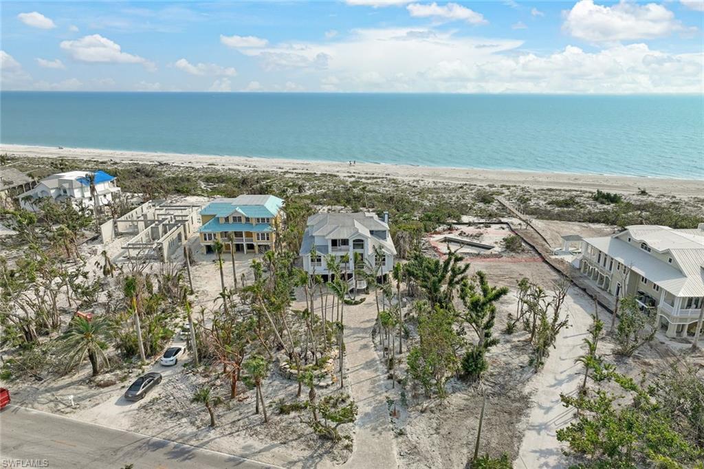 This beautiful Beach House is situated along the broad shell lined shores of prestigious West Gulf Drive. The 4 BR+ Den open floorplan is ideal for entertaining featuring decks of nearly each room. Outstanding panoramic direct Gulf views overlooking tropical landscaping complete this welcoming paradise. The home is light and bright, boasts a soaring entryway, glass railings, oak hard wood floors, a gas fireplace, plantation shutters, crown molding, impact glass and a tranquil pool and spa. The bright and spacious eat in kitchen with granite counter tops and Viking stainless steel appliances includes plenty of storage and pantry space. The Master Suite has been appointed with custom built in and closets, travertine marble, double vanities, and a shower with views. Property also includes an elevator from the interior parking level through the top floor, a spacious garage level, central vacuum, two zone HVAC and more. This property has been affected by Hurricane Ian.  Most damaged drywall has been replaced in the home since photos were taken, as well as damaged siding, pool equipment and more. Repairs are ongoing.