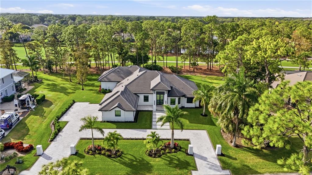Pond Apple perfection. Completely reimagined in 2024–2025, this exceptional residence in Quail Creek Country Club offers a rare blend of architectural refinement, modern luxury, and thoughtful expansion, delivering the look and feel of new construction within one of Naples’ most established golf communities. A 1,000± square-foot addition introduced a second luxurious primary suite, bringing the home to 4 bedrooms, 2 primary suites, a private office, 5 full baths, and a 3-car air-conditioned garage, totaling approximately 4,100 square feet under air. The home has been fully rebuilt from the inside out, including a redesigned front elevation with a striking modern luxury entry portico, instantly elevating curb appeal. Inside, soaring 14–16 foot ceilings, 10-foot Marvin impact windows and doors, floor-to-ceiling tile details, custom feature walls, and extensive downlighting define the clean, contemporary aesthetic. The chef’s kitchen is a true showpiece, featuring Wolf and Sub-Zero appliances, a 6-burner Wolf gas range, custom cabinetry, exposed beams, and seamless flow into the main living and entertaining spaces. A custom wine wall and wet bar with Sub-Zero refrigerator further enhance the home’s entertaining appeal. Every major system has been replaced or upgraded, including three new air conditioning systems, a new roof, spray foam insulation, new insulated garage doors, electric blinds throughout, and fully replaced and resized hurricane-impact windows and doors. Outdoor living has been completely redesigned, highlighted by a total pool renovation with an added sun shelf and elegant marble decking, creating a true resort-style setting. A covered lanai with outdoor kitchen, Storm Smart hurricane screens, and peaceful views of the 13th fairway with a fountain visible in the distance complete the outdoor experience. The property also features new irrigation, new sod, professional grading, and a bold modern square brick-paver driveway. This move-in-ready residence offers the rare opportunity to enjoy new construction quality, design, and systems in a premier golf community, combining timeless surroundings with today’s most sought-after luxury finishes.