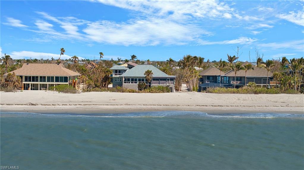 Located on the shores of Sanibel Island, this one-of-a-kind raised 4-bedroom, 4 ½-bath Gulf Pines home offers unrivaled views and privacy with 110 feet of direct Gulf frontage. Upon entering, you're greeted by a stunning two-story glass atrium garden that brings the outdoors in, filling the home with natural light and hues of the sea. The spacious primary suite features a sundeck overlooking the Gulf, his and her bathrooms with separate tub and shower and custom built-ins. Two charming guest rooms are located in the main house, including one with a private porch and breathtaking ocean views. A separate guest suite, connected by a covered walkway, can also serve as an office or den. The chef’s kitchen is a culinary dream with granite counters, Miele dishwashers, Wolf ovens, Sub Zero fridge, and more. With vaulted ceilings and an open concept design, the home flows effortlessly to expansive wraparound lanais—ideal for entertaining. In addition, there is a home office, large laundry room, tile and wood floors, and impact windows. The community pool and tennis courts are just steps away. This home is offered turnkey and ready to move right in, your tropical oasis awaits!