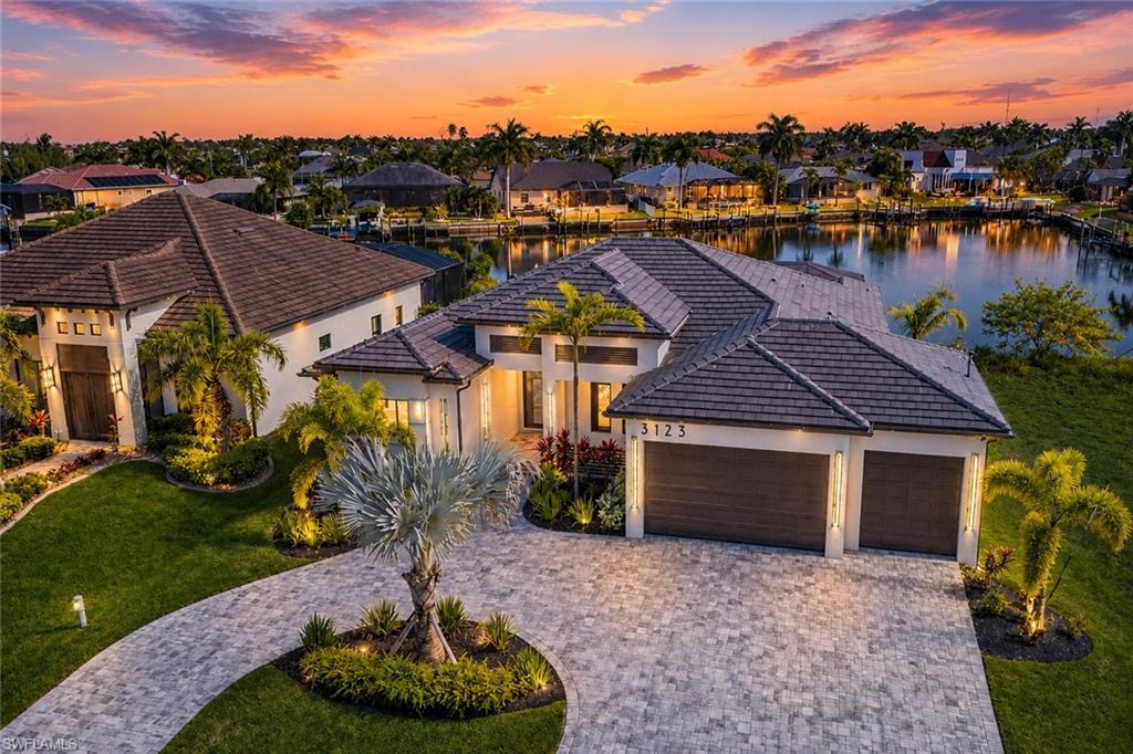 Experience the perfect fusion of luxury, comfort, and contemporary coastal living in this newly completed 3-bedroom + den, 3-bath waterfront MASTERPIECE with an expansive 3-car garage. Offering 2,200 square feet of impeccably crafted living space, this exceptional Gulf-Access home is ideally situated a block from Surfside Blvd in one of Cape Coral’s most sought-after neighborhoods, overlooking a stunning 350-foot-wide canal. From the moment you enter, soaring ceilings, designer finishes, and an airy open-concept floor plan create an atmosphere of sophistication and effortless elegance. 

The modern kitchen is a true centerpiece, showcasing a dramatic quartz waterfall island with seating, premium Kitchen Aid appliances, a sleek designer backsplash, and a custom coffee bar—perfect for both everyday enjoyment and memorable entertaining. The spacious great room is highlighted by a custom media feature wall with an 85” TV and electric fireplace, while striking 12-foot coffered ceilings add architectural character and a grand sense of space. The luxurious owner’s suite is a private sanctuary, offering direct lanai access, dual oversized walk-in closets, floating vanities, a freestanding soaking tub with designer tile accents, and a beautifully crafted walk-in shower that delivers a spa-inspired experience. Step outside and discover the ultimate Florida waterfront lifestyle. The expansive covered lanai overlooks a heated pool and spa and features an outdoor grilling station, comfortable lounge area with mounted TV, and abundant space for entertaining, relaxing, and enjoying spectacular sunset views year-round. 

Equally impressive, the exterior showcases a circular paver driveway, lush tropical landscaping, and a sleek tile roof that perfectly complements the home’s modern coastal design. Fully completed and move-in ready for its first owner, this remarkable residence offers an unmatched blend of style, location, and waterfront living. For those seeking a luxury Gulf-access home without compromise, this property is truly in a class of its own. No HOA's and No Assessment Balance! Schedule your private showing today and experience Cape Coral waterfront living at its finest.