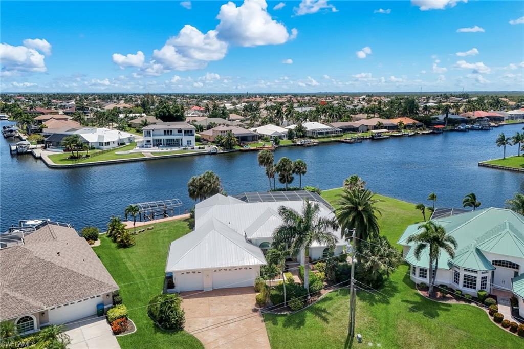 Experience true Southwest Florida waterfront living in this exceptional Gulf-access pool home located in the highly desirable SW Cape Coral area. Situated on an oversized lot with nearly 200 feet of water frontage, this property offers stunning wide-water views, southern rear exposure for all-day sun, and an unforgettable boating lifestyle. Enjoy a fun and scenic ride out to the Gulf with popular waterfront restaurants conveniently located along the way. This home is loaded with upgrades and features designed for comfort, luxury, and peace of mind. Boaters will appreciate the private boat lift and quick Gulf access, while the oversized pool and spa create the perfect outdoor retreat for entertaining or relaxing in the Florida sunshine. Inside, the home is being sold turnkey and fully furnished, making it completely move-in ready or ideal as a vacation rental investment. The spacious layout includes granite countertops in both the kitchen and bathrooms, a luxurious master suite with both a soaking tub and separate shower, and the convenience of two AC units for efficient climate control throughout the home. Also one of the garage spaces can also be temperature controlled. Additional highlights include a durable metal roof, 3-car garage, impact windows and doors, electric and manual hurricane shutters, and all city assessments fully paid! This is the complete Florida waterfront package — boating, outdoor living, luxury features, and prime SW Cape Coral location all wrapped into one incredible property.
