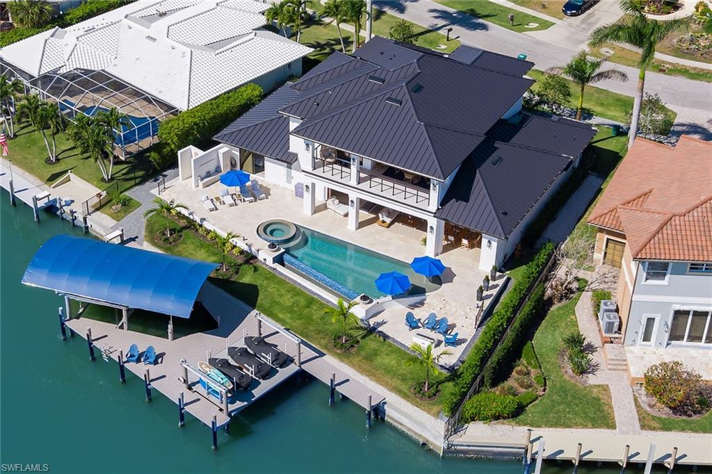 Your idyllic island retreat was newly built in 2022 and showcases expansive water views, SE exposure for plentiful natural light and a location that's just seconds to the river for super-fast, direct boating access. Ready for you to enjoy immediately, this impeccable 5-BR, 5.5-BA open-concept interior is offered turnkey furnished and displays voluminous coffered ceilings, crown molding and engineered hardwood floors. A linear fireplace warms the living room where impact-resistant pocket glass sliders seamlessly blend indoor/outdoor living. The chef’s kitchen features top-quality stainless appliances, custom cabinets, gas cooking, walk-in pantry, designer lighting and oversized waterfall island. Equal parts comfort and style, the generous master suite showcases tray ceilings, water vistas, custom walk-in closets and opulent 5-piece en suite. A paradise like no other, the expansive lanai has a full outdoor kitchen, fire pit and a heated saltwater pool with spa. Your composite dock comes with a covered 20K-lb boat lift and 3 Jet Ski lifts. Adding further appeal are tankless HW heaters, security, whole-house generator, electric shutters and oversized 3-car garage with epoxy floors.