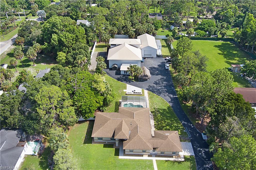 Rare opportunity! This one-of-a-kind 2.34 acre gated compound in the heart of Naples offers 8,735 total square feet across an immaculate main house with pool, a stunning guest apartment, and two massive garage/workshop buildings, all completely fenced with a huge paved circular driveway and room for up to 30 vehicles. The 3 bedroom, 2 bath main house with pool totals 2,935 square feet and features a whole house R/O system and neutral glazed Travertine tile flooring throughout. The beautiful kitchen offers high level granite countertops, custom maple cabinetry, a vaulted ceiling, stainless steel appliances, and an eat-in area with separate dining and living rooms. The spacious living area enjoys a great view of the screened in pool with outdoor firepit and Tiki hut/bar. The fantastic family room features floor to ceiling maple cabinetry, double French doors, a closet, and a gated breezeway leading to the 2 car garage, and hurricane panels protect the windows. The generous main bedroom offers pocket sliders and a deep walk-in closet, while the main bath includes a tub, shower, double sinks, high level granite, and lovely cabinetry. Both guest bedrooms are nicely sized, the guest bath features a tub/shower combination with high level granite, and a stackable washer/dryer is included. The stunning 1,000 square foot one bedroom guest apartment offers luxury vinyl flooring, a deep walk-in closet, KitchenAid stainless steel appliances, a pantry, quartz countertops, silent fans, an oversized shower, and a Samsung washer/dryer with built-in cabinets, plus a porch with breathtaking Gulf of America sunset views. The two additional garages/workshops total 4,800 square feet with three 14x14 insulated hurricane garage doors, room for trailers and trucks, and 2 RV hookups, one inside and one outside, with 110 or 220 power. The large garage is built on 10 inch plus reinforced concrete designed to handle extra heavy vehicles. All buildings have separate A/C, and one garage includes a bonus space perfect for a workshop, home office, or game room. A metal roof covers the guest house and garages, with spray foam insulation on the apartment and shed, PVC interlocking panels on the garage ceilings, security cameras, an alarm system, and a remote front entry gate. Mango, pineapple, and tangerine trees add tropical charm to the grounds. The location is superb, just minutes to I-75, Coastland Center, Freedom Park, downtown Fifth Avenue South, Gulf of America beaches, schools, shopping, dining, and entertainment.