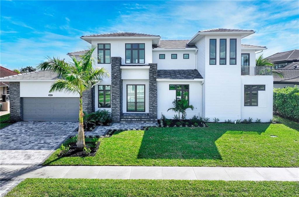 Brand-new stunning contemporary coastal waterfront estate offering exceptional value for new construction of this scale. Designed for light-filled luxury, this 5 BED | 5.5 BATH residence features a dramatic entry and a stunning two-story great room with soaring ceilings, clerestory windows, and an architectural bridge overlooking the open living, dining, and chef's kitchen. The kitchen was built to impress, with a massive quartz island, GE Café stainless appliances, 6-burner gas range with double ovens, dual refrigerators, and a custom walk-in pantry. The ground-floor primary suite is a spa-inspired retreat with soaking tub, custom shower, dual vanities, and elegant built-ins. Two additional first-floor bedrooms include a waterfront en-suite with lanai access, plus a split guest bedroom with nearby full bath. A private elevator leads upstairs to two more en-suite waterfront bedrooms, a family room with balcony, and a flexible loft—ideal for lounge, tech space, or game room. Expansive impact sliders and bold modern windows create seamless indoor-outdoor living. Outside, enjoy a zero-edge pool with infinity spa, cascading jacuzzi waterfall, and a spacious tongue-and-groove lanai, a summer kitchen, dining, and lounging areas—plus a pool bath. A 2010 seawall is in place, ready for your custom dock. Additional highlights include smart home features, oversized 2-car garage, 400-amp service, irrigation, fencing to the waterfront, and ambient landscape lighting. Just blocks to Residents' Beach, with quick Gulf access via Smokehouse Creek—this is luxury modern Marco Island waterfront living at a price point that's hard to match for new construction.
