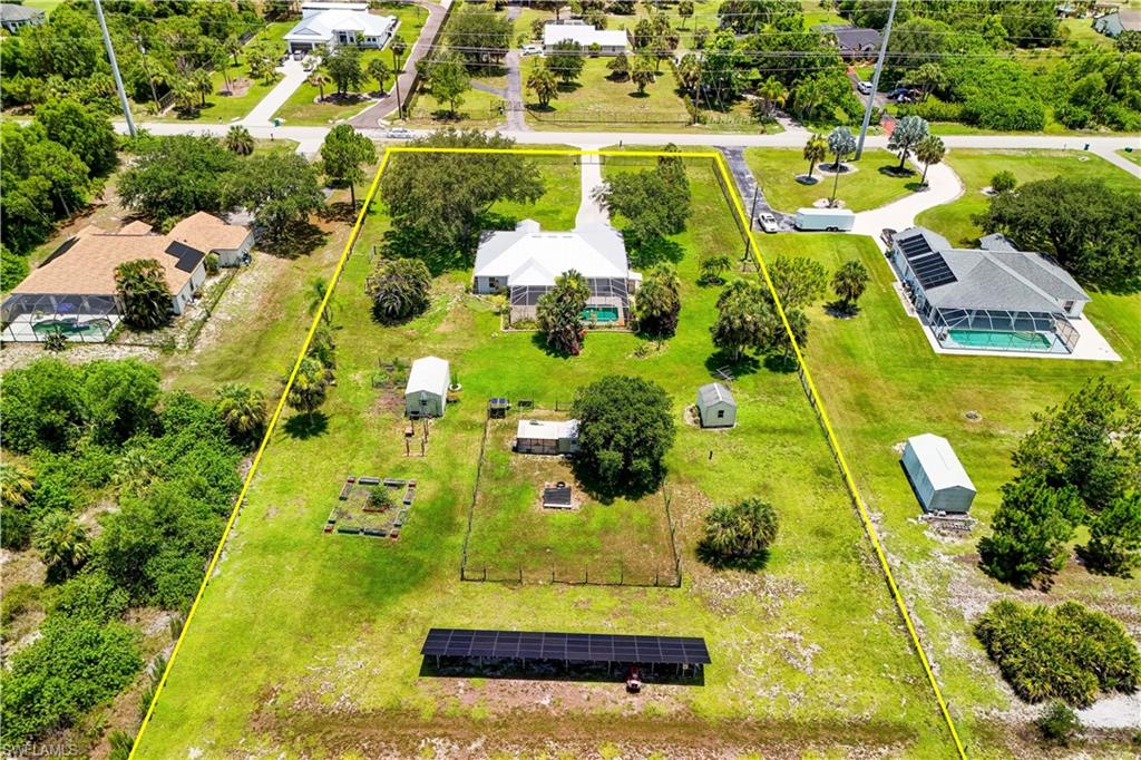 POOL HOME WITH METAL ROOF ON 2.73 FULLY FENCED ACRES & PAID-OFF 48-PANEL SOLAR SYSTEM! Enjoy the freedom of Golden Gate Estates living in this beautifully maintained, energy-efficient 3-bedroom plus den, 2-bath pool home, offering no HOA restrictions, privacy, and room for RVs, boats, and future expansion. Situated on 2.73 CLEARED AND USABLE ACRES, this FULLY FENCED property with an ELECTRIC ENTRY GATE offers a private retreat complete with a screened-in POOL AND LANAI, large GARDEN AREA, THREE STORAGE SHEDS, and a CHICKEN COUP with its own dedicated solar system, plus abundant space to build a workshop, barn, or guest house. Inside, the thoughtfully designed SPLIT-BEDROOM floor plan features soaring vaulted ceilings, granite countertops, formal dining area, surround sound system, and a versatile den that is perfect for a home office, media room or playroom. The spacious primary suite includes a WALK-IN CLOSET, an ensuite bathroom with soaking tub, and separate walk-in shower, creating a comfortable private retreat. Two other bedrooms and a full bathroom create a comfortable space for family, guests, or work-from-home needs. Major improvements provide exceptional value and peace of mind, including a METAL ROOF (2018), NEW HVAC (2024), POOL PUMP (2023), IMPACT WINDOWS THROUGHOUT, NEW FENCE & ELECTRIC ENTRY GATE (2023), NEW REFRIGERATOR & MICROWAVE (2024), NEW BEDROOM CARPETS, REVERSE OSMOSIS SYSTEM, and an EV CHARGER. One of the property's most impressive features is the FULLY PAID-OFF 48-PANEL SOLAR SYSTEM, which powers the home and helps keep average electric bills at approximately $22 per month. Conveniently located in a rapidly growing area, near shopping, dining, schools, and everyday amenities, this property offers the perfect balance of privacy and accessibility. Whether you're looking for a family home, hobby farm, or simply a place to enjoy the Southwest Florida lifestyle, this exceptional Golden Gate Estates property checks every box. THIS PROPERTY QUALIFIES FOR A 1% LENDER INCENTIVE IF USING PREFERRED LENDER, INQUIRE FOR MORE DETAILS** (Renderings that showcase furniture have been virtually staged)