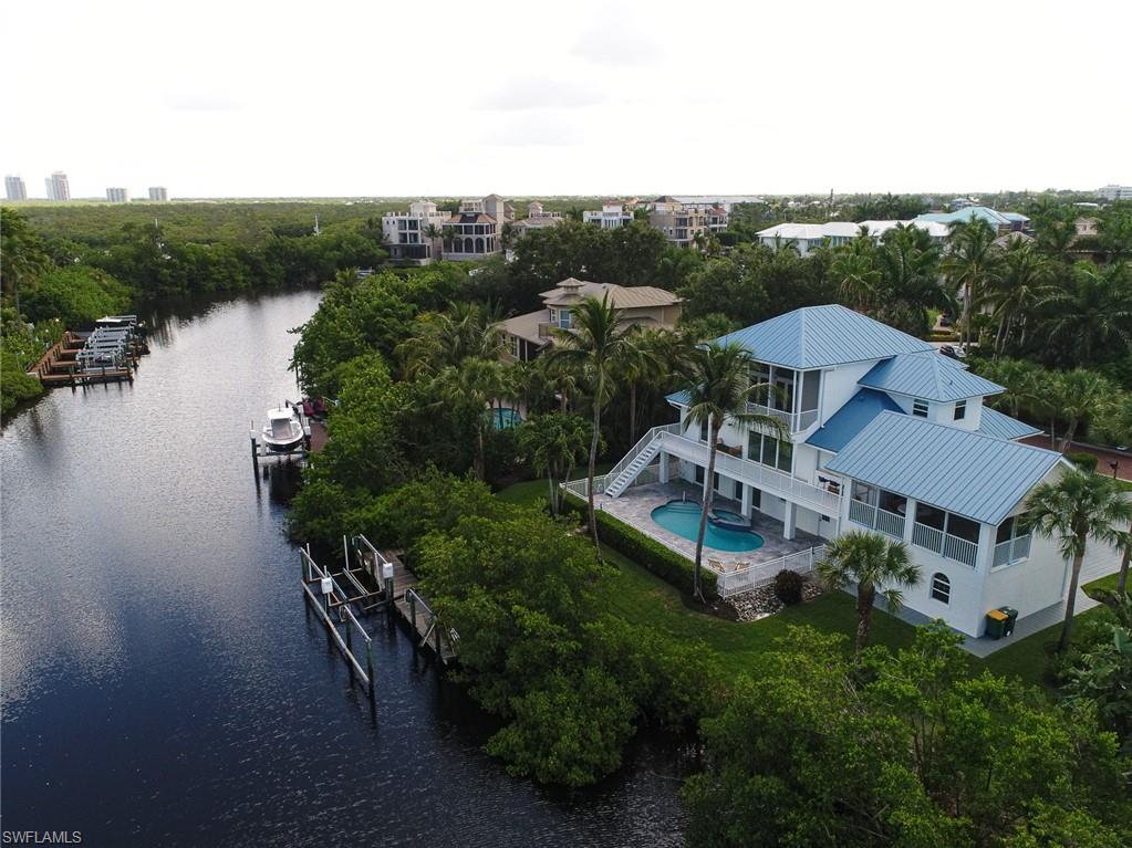 This renovated Southport on the Bay waterfront luxury home was just completed 2022. Southport on the Bay is a gated community located in beautiful Barefoot Beach, one of North Naples most sought after locations. This home offers direct gulf access via private boat dock as well as coveted private beach access. The exterior features Western exposure sunsets, new hurricane impact glass, standing seam aluminum roof, and pool & spa. The interior was professionally finished & decorated. Grand living room offers clean modern lines, oak plank flooring, kitchen w/custom cabinetry, beautiful center island, gas range cooking, waterside breakfast bar/work station, oversize covered lanai w/screens & shutters, outdoor kitchen w/gas grille, & extensive waterfront lounge space, a dedicated dining room full of natural light & 2 guest suites w/baths. The master level is a massive private space w/soaring ceilings, master den/office.  Master bedroom and private lanai overlook the pool & waterfront. The large master closet includes a private laundry. The master bath offers his and her vanity, soaking tub, and an XL glass shower. The ground level offers 4 car garage & unfinished space - boat dock As-Is.
