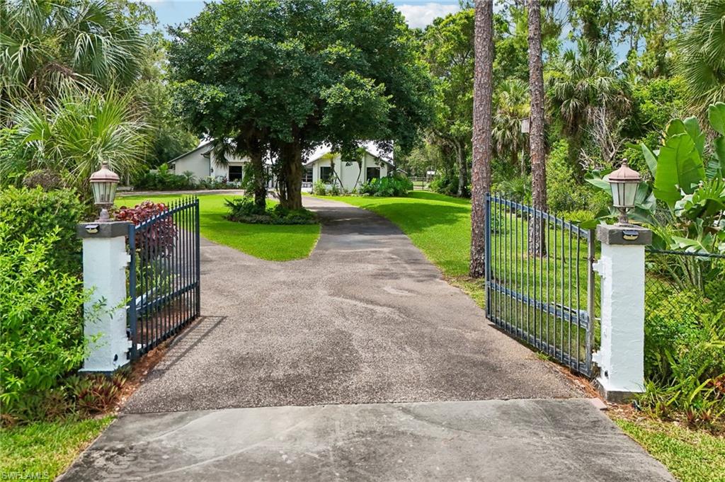 Welcome to your private retreat! Nestled on a beautifully landscaped 2.5 acre lot surrounded by mature trees and lush tropical greenery, this stunning single-story residence offers the perfect blend of modern comfort, privacy, and timeless curb appeal. Inside, you'll find bright, open living spaces filled with natural light. The heart of the home is a recently remodeled chef’s kitchen featuring an oversized quartz island, custom cabinetry, and premium stainless-steel appliances. Designed for entertaining, the kitchen opens seamlessly to surrounding living spaces, creating a warm and inviting atmosphere. Lounge by the beautiful fieldstone fireplace, shoot a game of pool, enjoy movies in the media room or head outside to enjoy the pool and hot tub. This home is an entertainer’s dream, with little to worry about with a whole home Generac generator, impact windows/doors, and one year old roof. Three-car garage provides plenty of room for an automotive enthusiast's vehicles and storage. 
Three outbuildings provide many opportunities including an air-conditioned finished living area with porch, perfect for a home office; a stable has space for animals with a fenced area in back. Don’t worry about how you will cut the grass as a John Deere lawn tractor will remain on property. Whether you're sipping your morning coffee, hosting friends, and family, or simply relaxing in the tranquility of nature, this property offers the lifestyle you've been searching for in a location close to beach, dining and shopping.