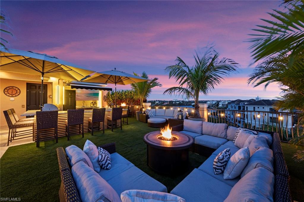 This magnificent waterfront residence epitomizes luxury and offers an exceptional coastal lifestyle and features 4 bedrooms plus den and 7 bathrooms. The standout feature is undoubtedly the vast 1,200 square foot roof deck, ideal for entertaining or simply enjoying the water views. Ascending to the fifth level via the elevator leads to a stunning garden area designed for both relaxation and social gatherings. Equipped with a fully stocked bar, generous seating options, built-in umbrellas, and a Sonos sound system throughout the property, it's a perfect setting for hosting up to 35 guests under the stars. The primary suite radiates opulence and comfort, featuring dual walk-in closets, a coffee bar for convenience, and a flexible area that can serve as an exercise room or study, providing a peaceful sanctuary within the home. The elevator connecting the ground floor to the roof deck adds an element of ease for both owners and guests. Each of the three guest bedrooms is equipped with its own ensuite bathroom, ensuring privacy and comfort for visitors. A striking spiral staircase enhances the architectural elegance of the home, leading from the ground level to the roof deck. The three-car garage, newly updated with an epoxy floor, along with additional parking space in front of each garage door, ensures plenty of room for vehicles and storage. Beautiful ceiling details throughout the home reflect the high level of craftsmanship and meticulous attention to detail that characterizes this beautifully renovated property. The home is conveniently located just a short stroll from popular beachfront venues like Doc's on the Beach, Coconut Jack's, and The Fish House, allowing residents to immerse themselves in the lively coastal ambiance. The updated pool and deck area, enhanced by a panoramic window screen enclosure, presents a serene view of the bay, along with boat lifts and Jet Ski docks, creating an idyllic outdoor retreat for leisure and enjoyment. Numerous covered seating arrangements offer ample space for soaking in the waterfront scenery. The modern quartz kitchen, with captivating views of the bay, offers a delightful backdrop for meal preparation, turning cooking into an enjoyable experience. This waterfront property encapsulates the essence of coastal luxury, offering an extraordinary blend of sophistication, practicality, and stunning vistas, promising an unparalleled living experience by the sea!