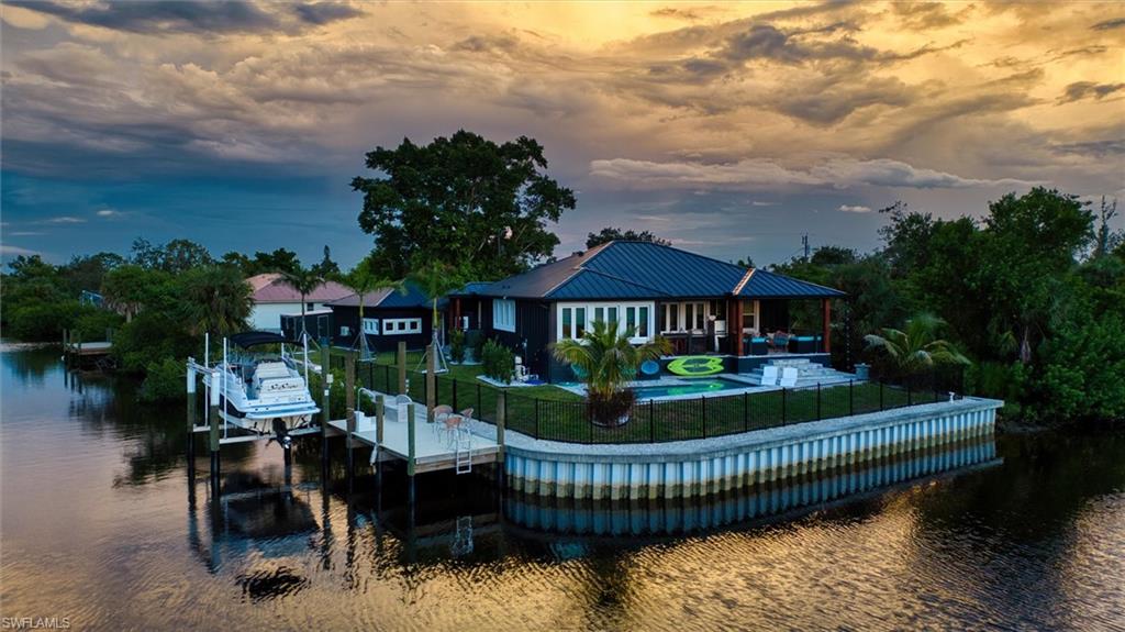 A One-of-a-Kind TREND SETTING Masterpiece on the Water! Welcome to 3001 Banyan Way, Punta Gorda, completed in 2024, where architectural artistry meets uncompromising luxury. Set on a prime waterfront lot with intersecting canal views, 211 feet of seawall, and remarkable sunsets, this residence was crafted with every imaginable upgrade to create a true designer dream home. Simply stunning! From the moment you arrive, the curb appeal is undeniable— ultra modern and powerful exterior colors inspire the senses. A visual delight are the many exterior accents including Hardi Trim Board and Batten cement siding, an expansive lighted retaining wall, offset garage and connecting breezeway with smart wood beam pillars. Professional landscaping with designer lighting, an interlocking three-piece paver driveway and an iron fence with three locking gates frame the back of the property all the way to the seawall. Step onto the Chicago replica brick front porch, beneath a tongue-and-groove ceiling with recessed lighting, and through an impressive iron entry door. Inside, every room tells a story of craftsmanship and indulgence. The living room stuns with Venetian plaster tray ceilings, dramatic beams, a 100-inch linear fireplace, and a full quartzite feature wall. The gourmet kitchen is a showpiece: Dolomite Blue quartzite countertops throughout, GE Café matte white appliances including a six-burner propane range, two under-counter refrigerators, and full-height subway tile with a quartzite shelf. A walk-in pantry and adjoining laundry doubles as a bar and prep space, featuring cobalt blue GE smart appliances, built-in storage, a liquor drawer, and a chandelier-lit window seat. The master suite is a sanctuary with Venetian plaster finishes, custom ceiling design, and a spa-like bath offering a freestanding tub under chandelier light, a walk-through shower with body jets, double marble sinks, and artistic feature walls. Additional rooms showcase true individuality, including a music room adorned with gold-leaf stucco, a bespoke feature wall, and a dramatic chandelier. Outdoor living reaches resort level. A saltwater, heated PebbleTec pool with LED lighting is surrounded by an expansive paved entertainment deck. The covered rear porch features tongue-and-groove ceilings, an outdoor kitchen with grill and sink, recessed lighting, ceiling fans, and dual French iron doors that invite seamless indoor/outdoor living. At the water’s edge, the composite dock is built for the serious boater, with shore power, a 12,000-lb lift, and oversized pilings ready for a roof structure. Enjoy a 15 minute boat ride along the Venice Waterway to Alligator Creek, then to Charlotte Harbor. Every detail is deliberate: spray foam insulation throughout, tankless water heater, hurricane-impact doors and windows, remote custom blinds, lighting integrated into the eaves and landscaping, the highest grade luxury vinyl plank and soap stone tile flooring, and a full-home generator with hook-up.