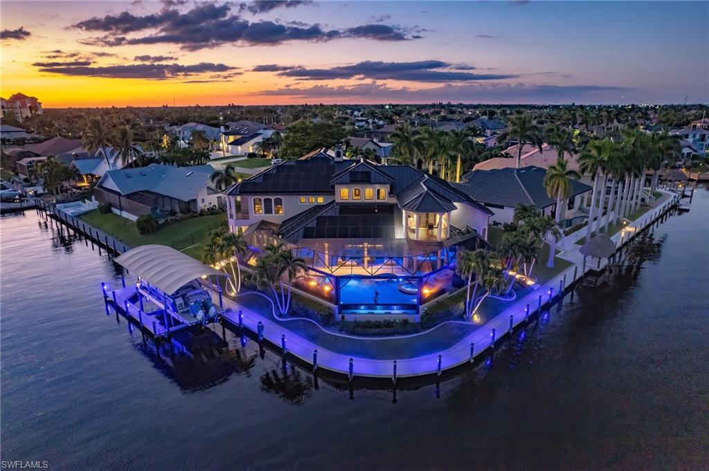 Sweeping intersecting canal and spreader canal views, direct no-bridge Gulf access just minutes to open water, 178 feet of seawall, wraparound composite dockage, a Captain's Walk, 35,000-pound boat lift, desirable southeast rear exposure, fully paid solar, whole-house generator, and a complete designer reimagination define this extraordinary waterfront estate just steps from Cape Harbour.

Positioned on one of Cape Coral's most coveted waterfront homesites, the property captures long panoramic water views while maintaining exceptional privacy. Inside, soaring 30-foot ceilings, a dramatic architectural staircase, and nearly 7,000 square feet of thoughtfully designed living space create an unforgettable first impression. The chef's kitchen features quartz countertops, premium appliances, a waterfall island, butler's pantry, and propane gas cooking, while a stunning 400-gallon saltwater aquarium serves as a one-of-a-kind focal point. The first-floor primary suite offers a luxurious retreat, complemented by an executive office, media room, and flexible guest accommodations.

Outdoor living reaches another level with what may be one of the finest lanais in Cape Coral. The resort-inspired setting features a disappearing-edge saltwater pool and spa, dramatic fire and water features, outdoor kitchen and bar, multiple gathering areas, architectural lighting, and lush tropical landscaping designed for year-round enjoyment.

Bring your yacht and enjoy deep-water access to waterfront dining, world-class fishing, barrier islands, and the Gulf of America just minutes from your dock. Additional highlights include an air-conditioned 3.5-car garage and negotiable furnishings.

A rare opportunity to own one of Southwest Florida's premier waterfront estates.
