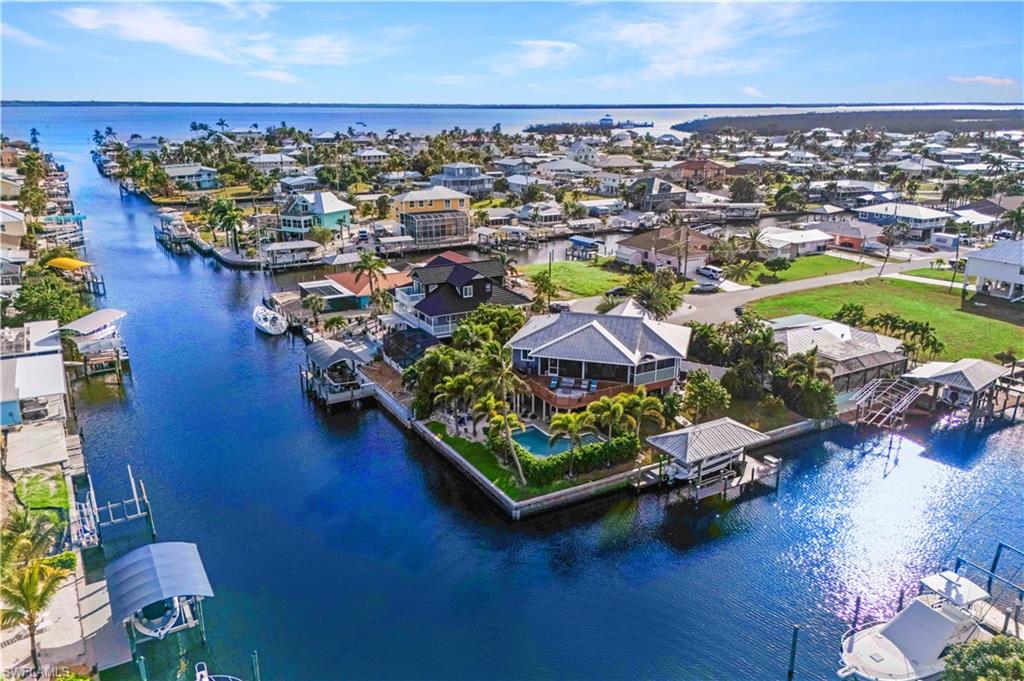 Tropical Waterfront Paradise with Endless Charm! Welcome to your own slice of paradise! Nestled on a peaceful cul-de-sac corner lot with 189 feet of stunning waterfront, this exceptional 4-bedroom, 3-bath home perfectly blends luxury, comfort, privacy, and Florida fun. Located on beautiful INTERSECTING CANALS, every day feels like a vacation.  Step outside to your private resort-style oasis—take a dip in the heated pool, relax by the firepit, get comfortable with a book on the hammock, or wiggle your toes in your very own playful sandy beach area. Boating enthusiasts will love the covered dock with lift, ideal for easy Gulf access and sunset cruises.  TWO MINUTES OUT TO OPEN WATER! Inside, discover a bright and inviting open floor plan designed for relaxing and entertaining. The gourmet kitchen is a chef’s dream, featuring stainless steel appliances, custom cabinetry, Corian countertops, a wine refrigerator and plenty of space for gatherings with family and friends. The main suite offers a peaceful retreat with scenic water views, while the versatile downstairs “in-law” suite which includes a full kitchen and laundry room, providing private accommodations for guests or extended family. Surrounded by lush tropical trees and vibrant landscaping, this home truly embodies the Florida lifestyle—a perfect balance of relaxation, recreation, and natural beauty. Whether you’re lounging by the pool, hosting sunset dinners, or setting out on a morning paddle, every moment here feels like a getaway.  Come experience the joy of waterfront living—where every sunrise sparkles on the canal and every sunset invites you to stay just a little longer.  Consider adding this home to your income producing portfolio by placing this Coastal Escape on the vacation rental market.  This home is in high demand all year!
