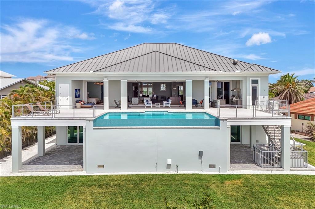 Welcome to 26906 McLaughlin Blvd, a modern coastal masterpiece nestled in the exclusive Carolands neighborhood of Bonita Springs. Completed in 2021 by renowned builder Damon Custom Structures Inc., this custom-designed residence offers an extraordinary blend of contemporary design, premium construction, and waterfront living on nearly half an acre of prime Gulf-access land. Built to meet or exceed all FEMA guidelines, this concrete fortress is elevated well above flood levels and fortified with over 35 hurricane-impact doors and windows, as well as electric hurricane shutters and screens securing the rear elevation for year-round peace of mind. Retrofitted with an essential home generator. 

This is not a spec home—it’s a true one-of-a-kind custom build with no expense spared in design or finish. With 4 spacious bedrooms—all with ensuite baths—and a private study, this home offers both flexibility and functionality. The primary suite is a secluded sanctuary featuring dual walk-in closets, direct access to the pool deck, and a spa-style bath with standalone tub, dual vanities, and an oversized glass-enclosed shower. Soaring coffered ceilings with custom wood detailing, wide-plank flooring, and expansive pocketing sliders blend indoor and outdoor living seamlessly. The chef's kitchen is a showstopper with quartzite countertops, a massive island with seating for six, Thermador appliances, custom wood cabinetry, and a generous walk-in pantry.

Step outside to your elevated resort-style pool deck—an entertainer’s dream—featuring a saltwater infinity pool, spillover spa, outdoor shower, and full summer kitchen with grill, sink, fridge, and bar-top seating. Enjoy sunrise bay views, watch dolphins and manatees glide by, or walk a few steps to the pristine sands of Bonita Beach. The property includes a private dock with direct access into Little Hickory Bay and the Gulf of Mexico, perfect for boaters and kayakers alike. A double-side garage provides ample space for 6+ cars, golf carts, or watercraft. The home and all the comforts operate off of a 1,000 gallon underground propane tank.   

Offered furnished with some exclusions, this estate is located in the sought-after Carolands community—a coastal enclave known for its oversized lots, estate homes, and strong redevelopment potential. With many original ground-level homes being replaced by new construction, this neighborhood promises long-term value and investment stability. Just minutes from fine dining, shopping, and entertainment at Mercato, Coconut Point, and Waterside Shops, and less than 30 minutes to RSW Airport, this is luxury living at its finest on Florida’s Gulf Coast.