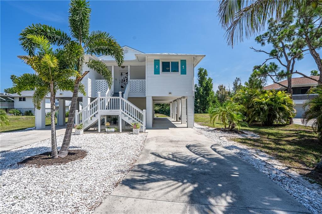 Amazing Opportunity! Newly Renovated, Gorgeous Island Style Stilt Home! Three Bedrooms, Two Full Baths, with a Split Floor Plan and on .49 Acres of Land! Now Available in the Desirable “The Nesting of Pine Island” Neighborhood. Welcoming Dual Entry Staircase, Lovely Open Front Porch and the Charming Entry Foyer Await Your Arrival. Enter the Bright, Large Living Room with French Doors that lead out to a Beautiful Screened Porch, Huge Open Deck and Spiral Staircase with Views of the Sprawling Back Yard! Gorgeous Large Kitchen with Custom Breakfast Bar, All New Cabinetry with Pull Out Drawers, Quartz Countertops, Glass Tile Back Splashes including the Breakfast Bar, Under Cabinet Lighting, Recess and Pendant Lighting, Tons of Counter Space, All Stainless Appliances, and a Pantry with Built in Cabinetry and the Full Size Stackable Washer and Dryer. This Open Kitchen is Adjacent to the Bright, Over Sized Gathering Dining Room. Nice Main Bedroom with Walk In Sized Closet and an En Suite Bathroom with Glass Door Shower, Stone Floor and a Separate Sink Area. Guest Bedrooms with Access to Full Guest Bath with Glass Shower Doors. Outstanding Space for up to Ten Vehicles with Two Long Driveways hosting approx. Four Under the Two Large Carports, and/or RV, Boats, Trailers etc.  Fantastic Large Under House Storage Room and/or Workshop for all of your Hobbies or Storage Needs. The Open Balcony with New Deck Overlooks the Large Fabulous Back Yard. Nearly a Half Acre of Land with Plenty of Room for a Pool or Your Perfect Vision! Central Water. Private Septic. Recent Updates Throughout Including: Luxury Vinyl Flooring Throughout, All New Fixtures, Fans, Blinds and Appliances. Total New Kitchen 2022/2023 and Pantry with New Built in Cabinetry, New HVAC 2021, Remodeled Bathrooms with New Showers and Toilets, 2023/2024. New Metal Roof, All New Hurricane Impact Windows and Front Door. New French Doors. New Tankless Water Heater 2024/2025. New Screen Enclosed Porch and New Decking on the Back Open Balcony 2024. New Decorative Shutters 2024. New Front Deck Railings 2025. Updated Spiral Staircase. Dates are approximates. Located is a Beautiful Lush and Tropical Neighborhood Setting located at the center of Pine Island only minutes to the Community Pool, Museum, Playground, Baseball Fields, Library, Shopping, Specialty Shops, Restaurants and a Short Drive to Pineland Marina and our Local Ferries. Move In Ready! This Special Island Home is Simply a Must See!