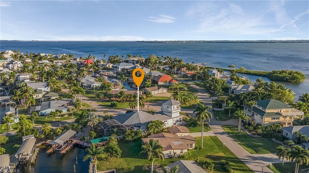 The ultimate in Florida Tropical Paradise Living!!!  Enjoy living the Vacation Lifestyle every day!  This lovely turnkey waterfront, screened pool, home with 3 bedrooms and 2.5 baths, also has a "lighthouse" with hand painted murals and 2 additional rooms!  The top floor has beautiful views of San Carlos Bay and Sanibel, with a balcony and walkway around the outside.  The 2nd floor room can be used as a craft/hobby/office or a 4th bedroom!  Enjoy entertaining with the centrally located kitchen with plenty of counter space, and then enjoy dining in the beautiful dining room with hand painted murals. The split bedroom plan offers privacy for your guest.  The lanai and pool area are outstanding with plenty of space for everyone, inside and out!  There are 2 boat lifts, one hard covered which held a 36' Tiara, with wrap around composite deck. The 2nd smaller covered lift is set up for a pontoon.  Enjoy the outdoor fire pit area, and a fun outdoor shower on the pool deck!  The 2+ car garage has cushioned garage floor mats, and a wonderful workshop area.  There are roll down hurricane shutters for all openings.  Don't let this one slip away!