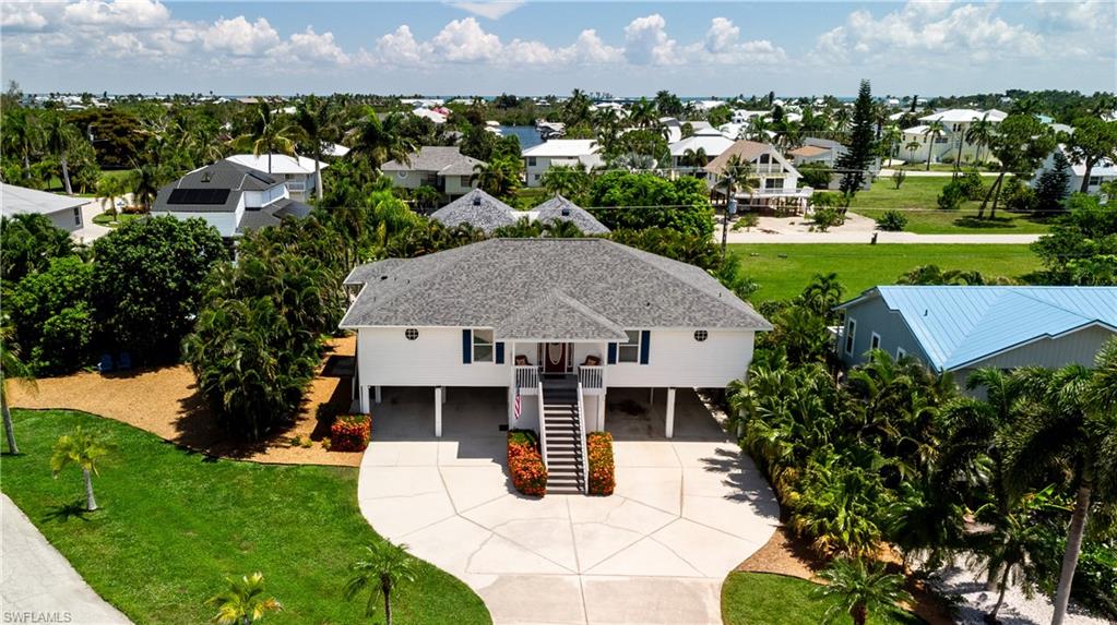 Captains Cove, Located at the North end of Pine Island next to Charlotte Harbor and the Gulf of Mexico. This 2/2 Home has vinal siding for easy maintenance, new Roof in 2023, Elevated, Tropical Island Style home.. Extra large lot ( there's extra land on the west side of the Areca Palm hedge !!!)  Ground floor has 4 parking spaces,  shop/storage, plenty of room for fishing poles and tools..!! Upstairs has a large long screened back porch, almost the length of the house... Tile & Carpet Floors, Open Kitchen/Living Room area, plenty of cabinets & drawers, "L" shaped breakfast bar and the living room with vaulted ceilings is large and airy...  Bath, utility-room and 2nd bedroom... Master suite has 2 closets, bath with dual sinks, shower & separate tub, and attached work-out room or office. There is a private boat ramp for Captains Cove property owners, as well as private Sewer. Next to Four Winds Marina and The Lazy Flamingo Restaurant.. Beautiful Island Location ..come and see today !!
