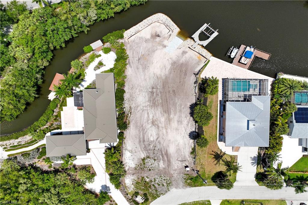 An extraordinary waterfront homesite offering a rare blend of scale, privacy, and direct Gulf access through Estero Bay. Set on nearly half an acre with approximately 123 feet of shoreline, this cleared property is a once-in-a-generation opportunity for the discerning buyer seeking an exceptional coastal lifestyle. A brand-new private boat ramp with 32 feet of out-of-water, a new dock with 10,000-pound Neptune boat lift, and newly installed rip rap create a remarkable foundation for effortless boating and waterfront living—just 5 minutes from the Gulf.
City water and sewer, with temporary power and active water service, allowing you to move from vision to execution with ease. Tucked near the end of a peaceful cul-de-sac, the setting offers a quiet sense of seclusion, with minimal direct rear neighbors and a backdrop that feels private and serene.
For those that need expediency in building  a signature residence, existing plans for a two-story home with five bedrooms, five baths, and a dedicated office are available for the buyer to use as-is or tailor with their own builder. With much of the groundwork already completed—including a soil test indicating no pilings required for the current plans—this is a rare chance to design and build a custom waterfront retreat surrounded by the beauty of Southwest Florida nature.